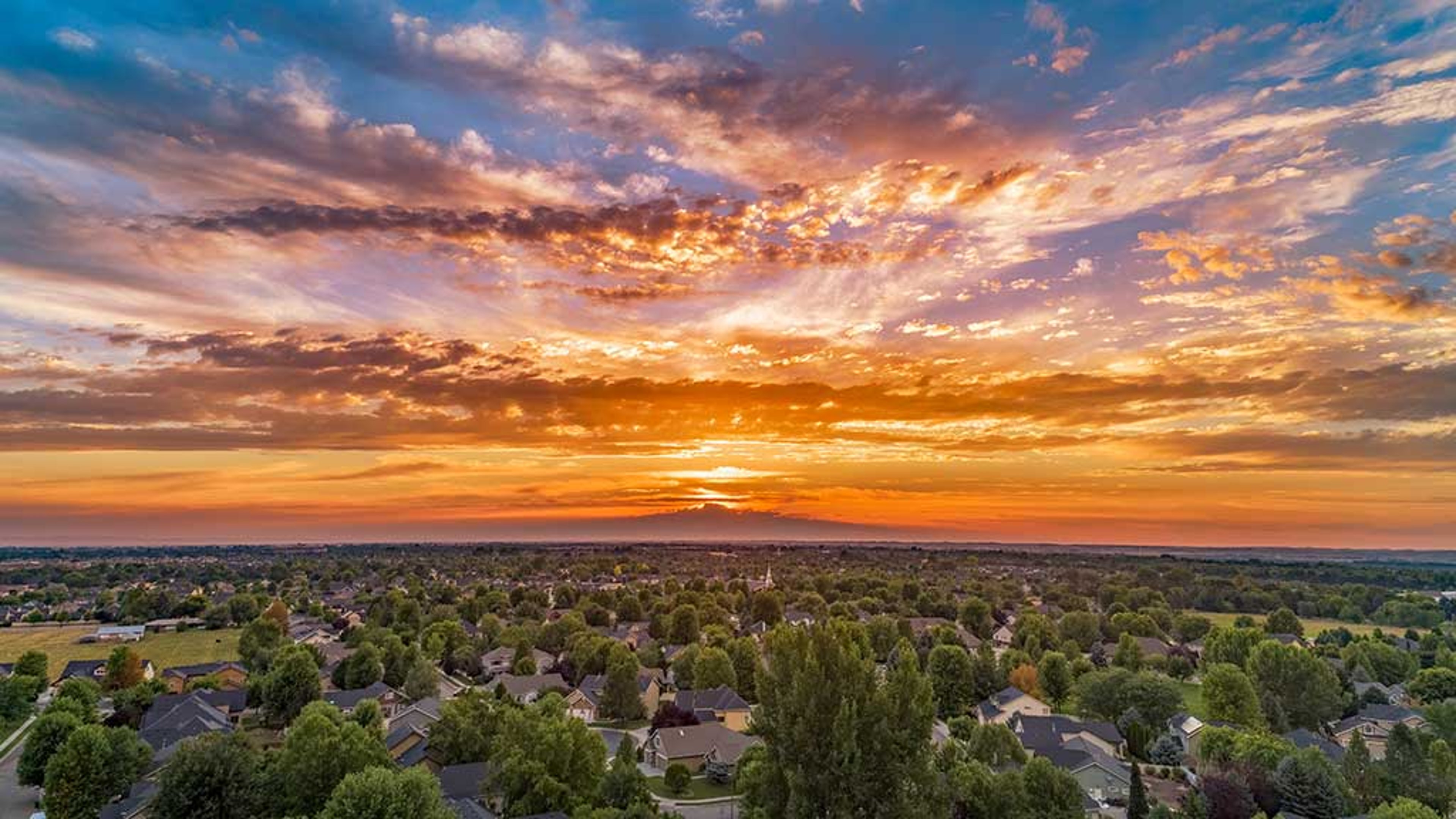 A vibrant sunset over the Treasure Valley, likely taken near Nampa, Idaho, with glowing skies and a peaceful residential landscape below.