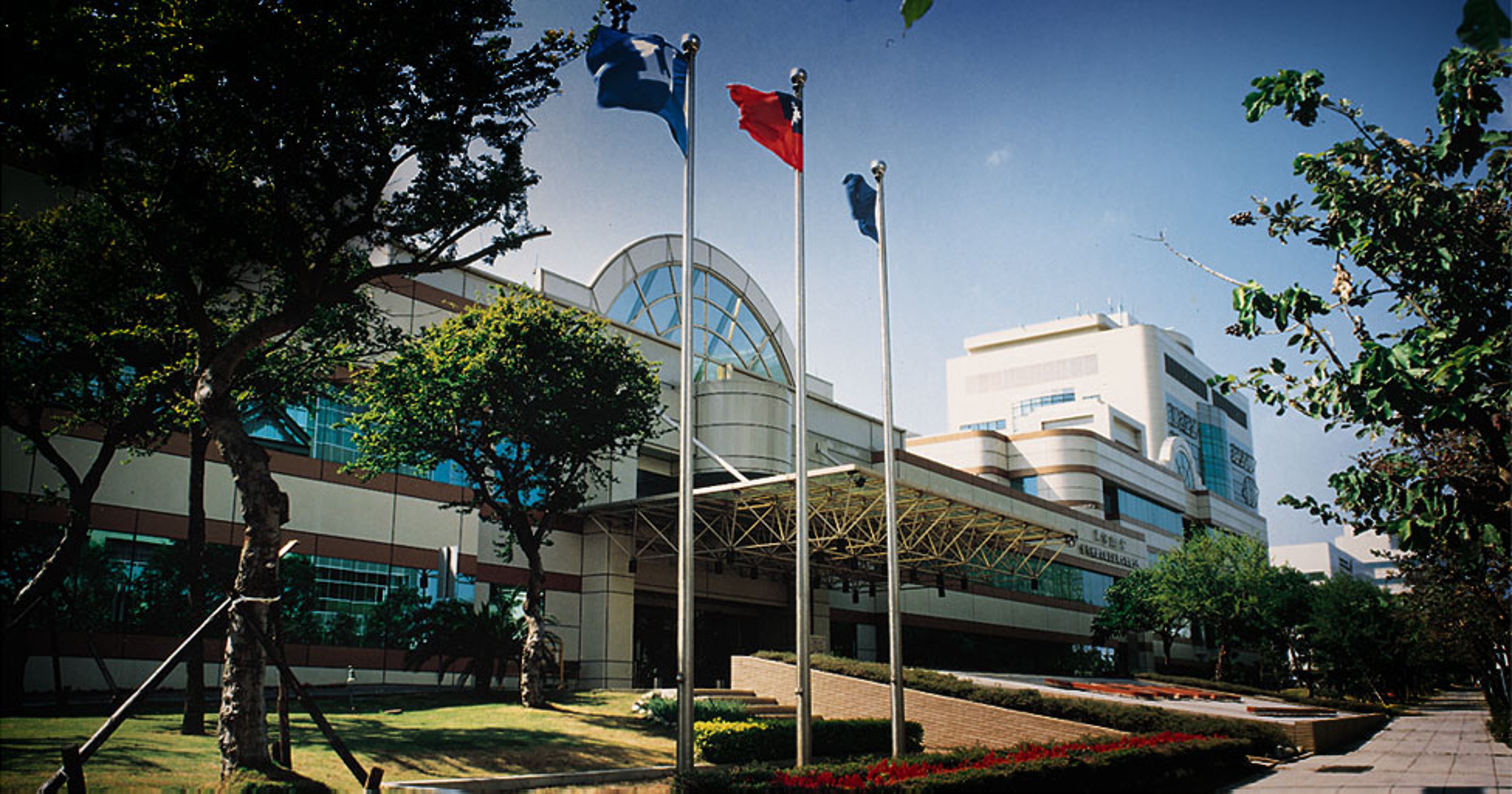 Semiconductor facility from the outside with three flag poles in front of the builing