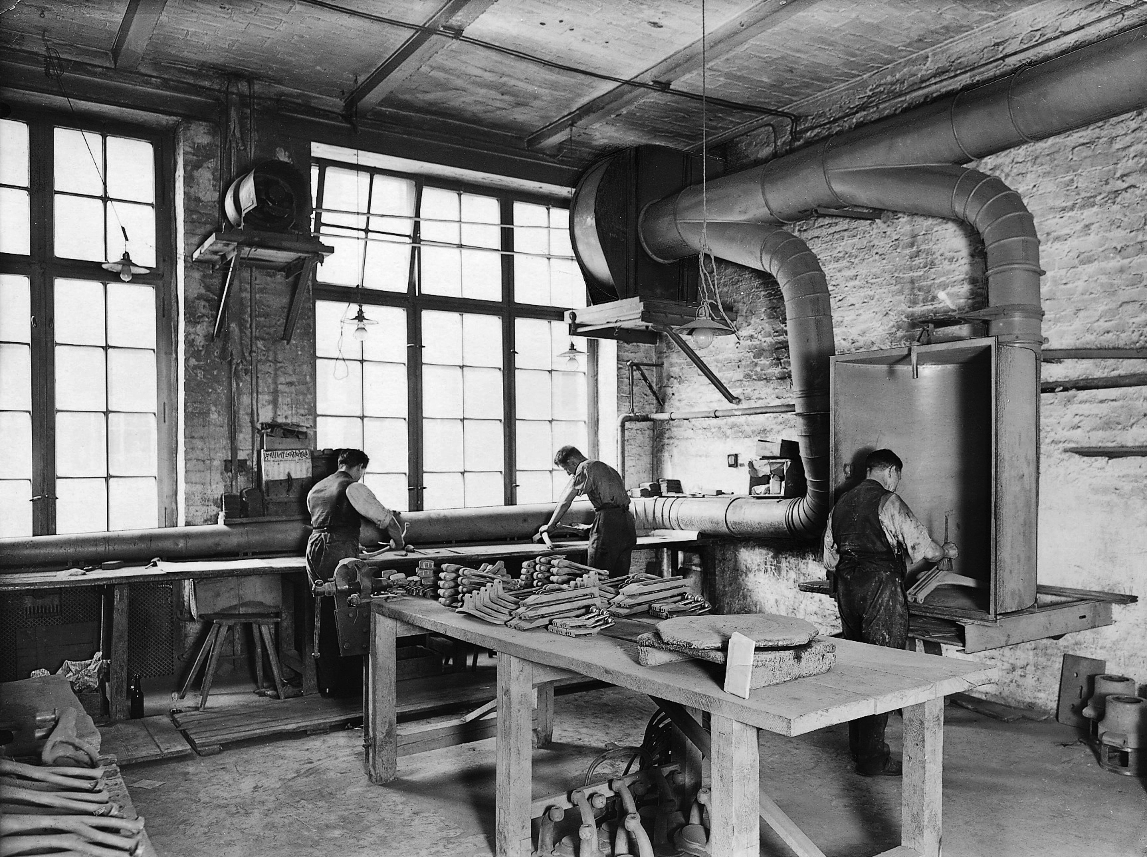Black and white photo from the 1910s showing employees working on a piece of air extraction equipment