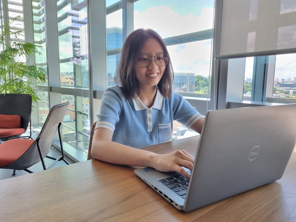 Exyte employee Oh Qi Qi sits on a desktop computer at work in an office. 