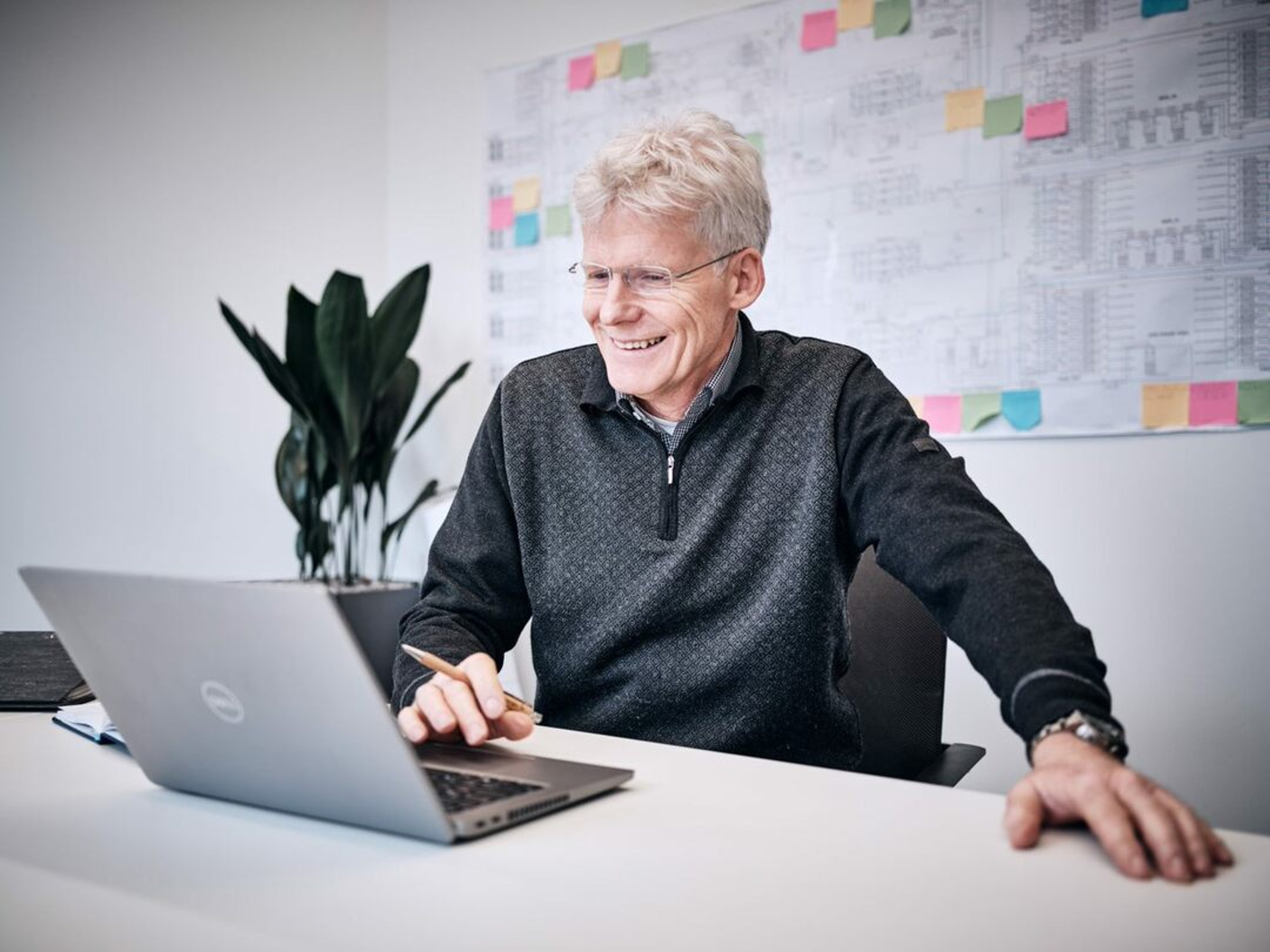 Manfred Engelhard, Senior Director Technology Management at Exyte, smiles while working at a computer. He plays a key role in Exyte’s mission to reduce Scope 3 emissions in AI data centers through sustainable design, smarter materials, and innovative energy systems.