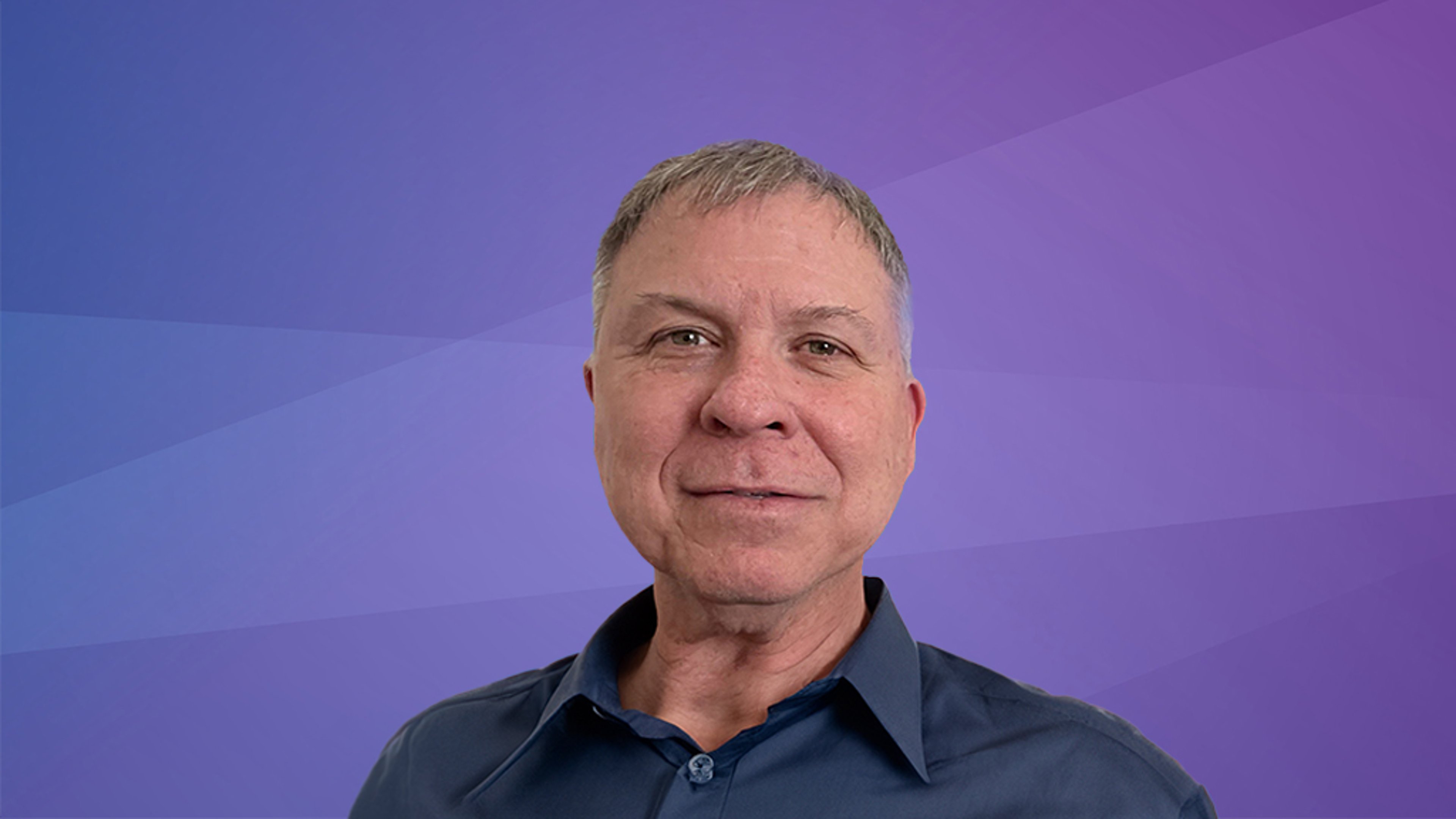 A professional headshot of Eduardo Galdo, smiling and wearing a dark blue shirt, set against a purple gradient background.