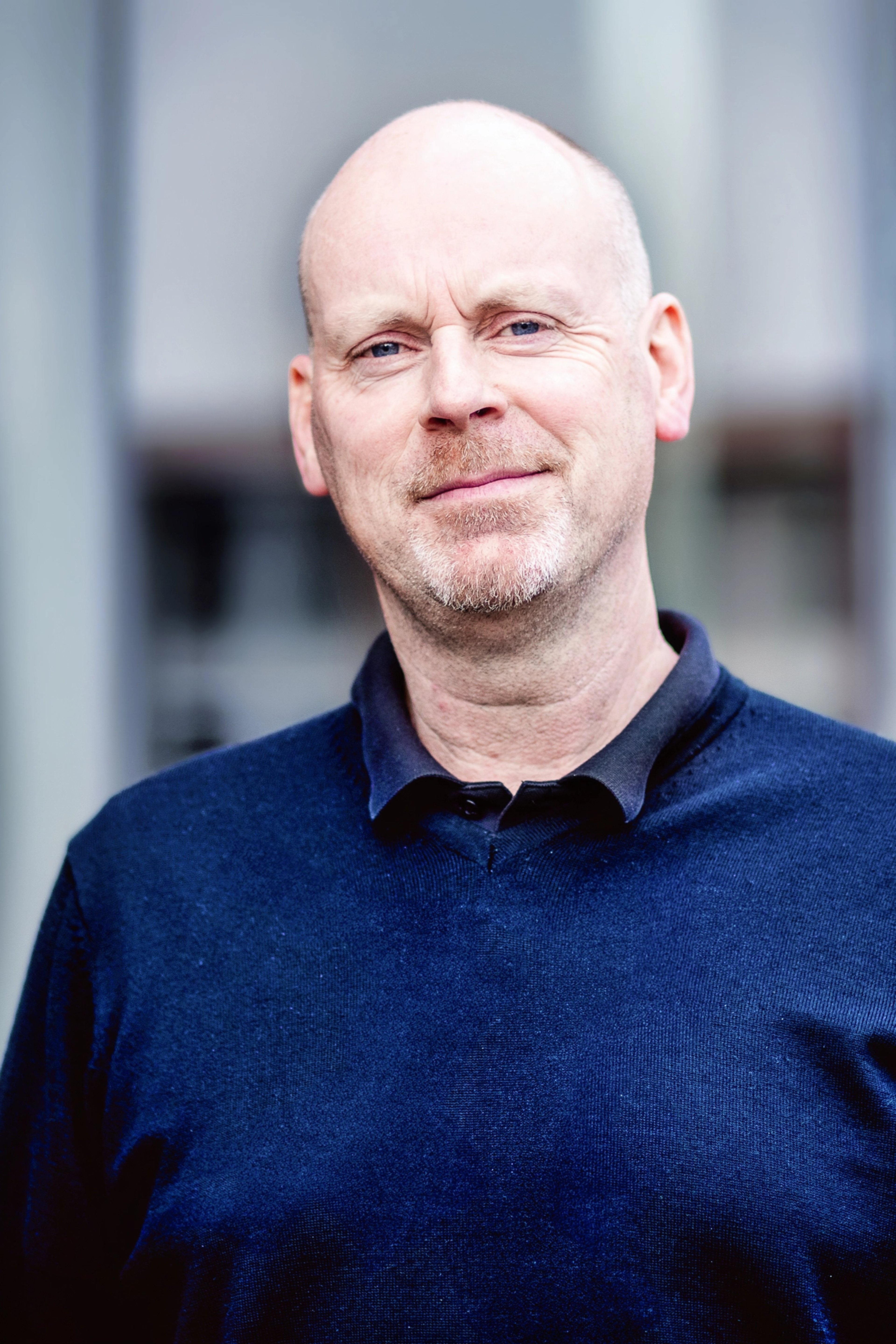 Alan Cassidy, standing outdoors, wearing a dark sweater and a collared shirt underneath. He is looking directly at the camera with a subtle smile.