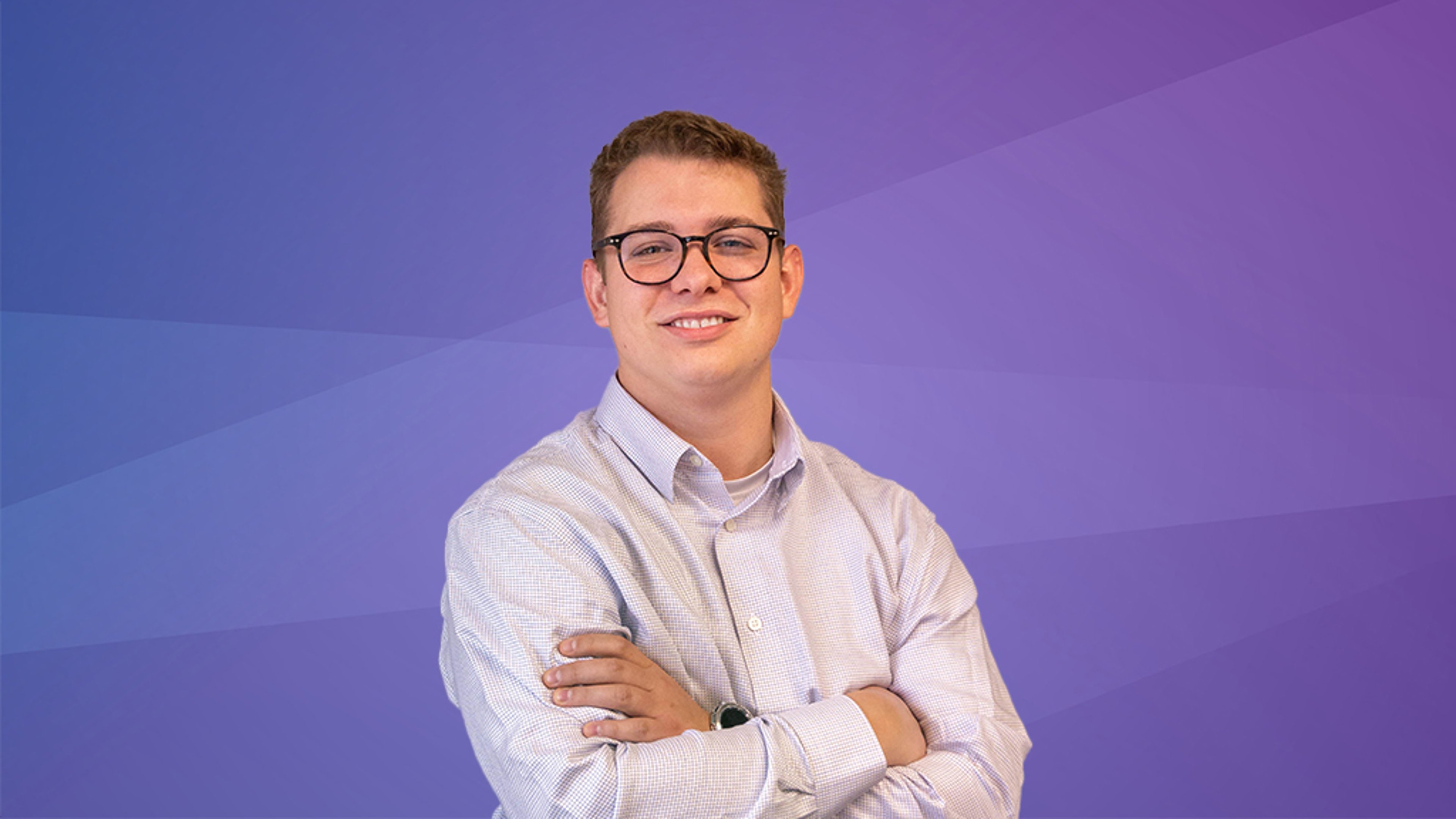 A professional headshot of Jacob Harris, smiling with his arms crossed, wearing glasses and a light-colored button-down shirt, set against a purple gradient background.