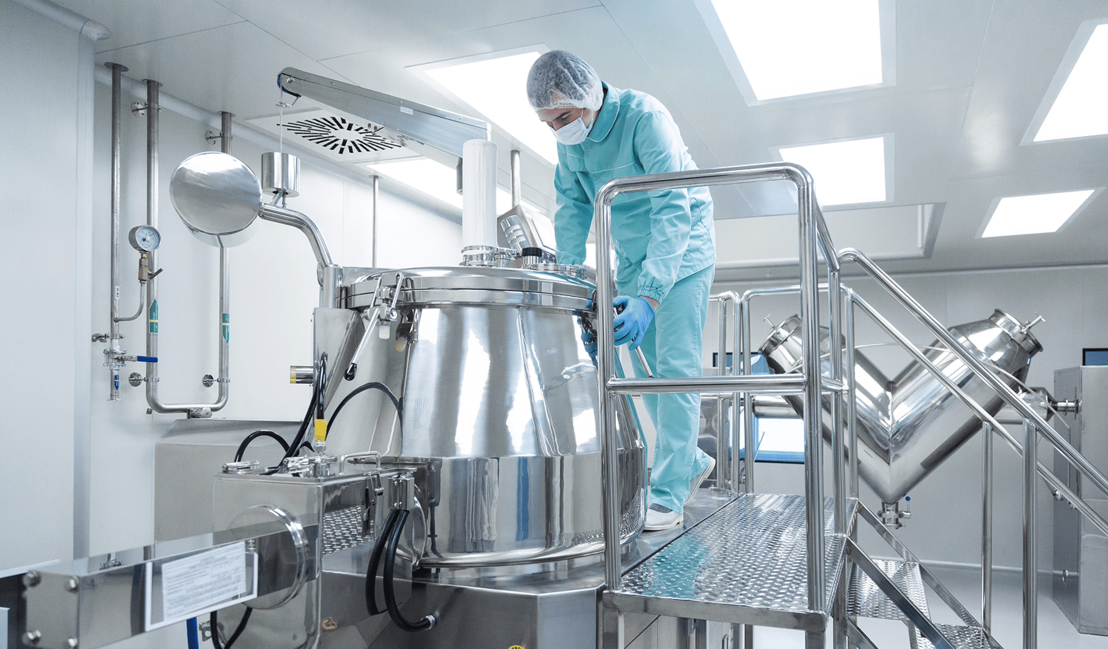 A technician working on advanced HVAC systems in a cleanroom environment with the Exyte logo visible, surrounded by complex ductwork and equipment, ensuring air quality and ventilation for precision manufacturing.