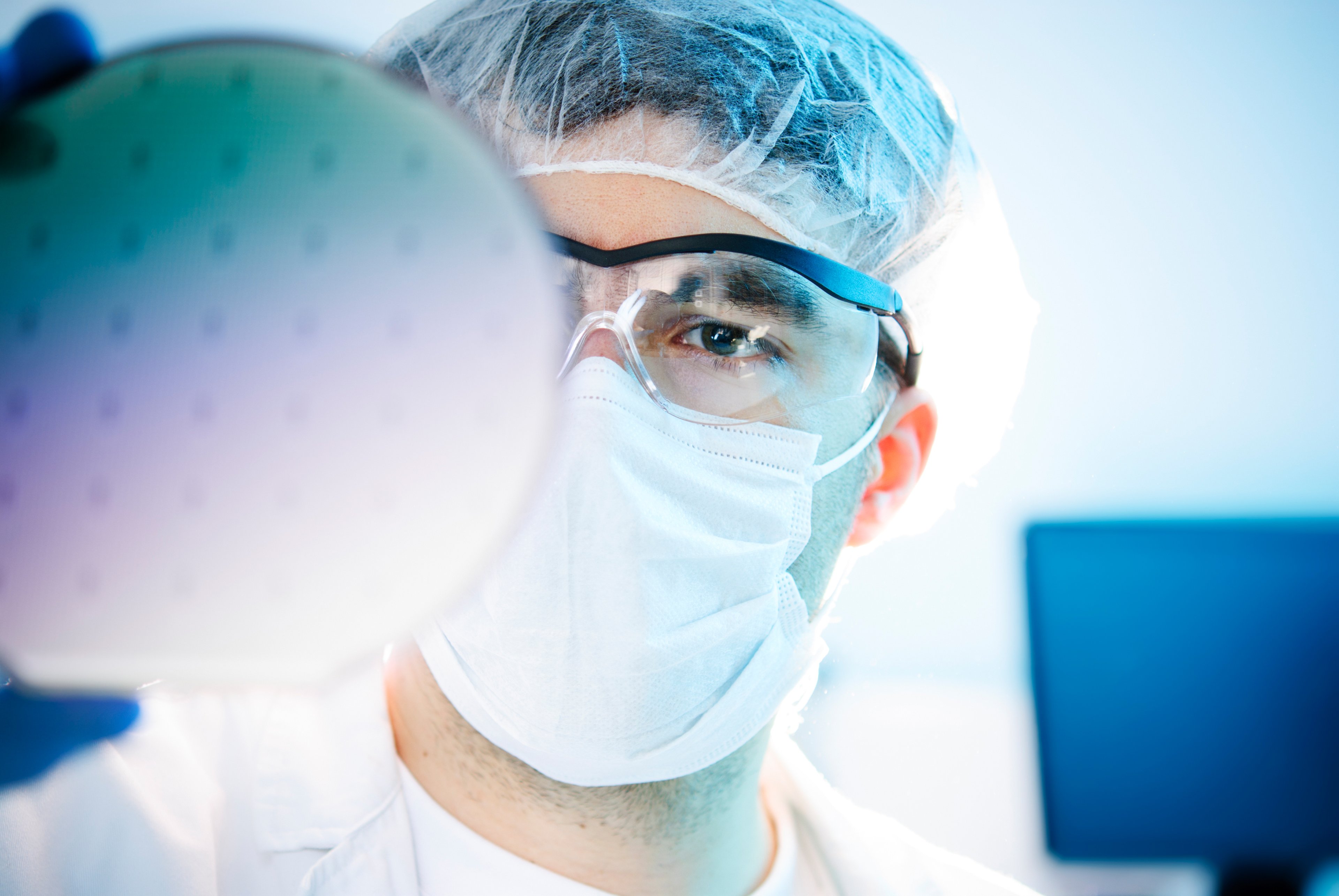 Person with cleanroom disposable gear investigating a wafer