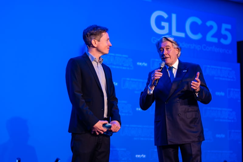 Exyte CEO Dr. Wolfgang Buechele (right) is on stage speaking into a microphone. On the left we see the host of the evening. 
