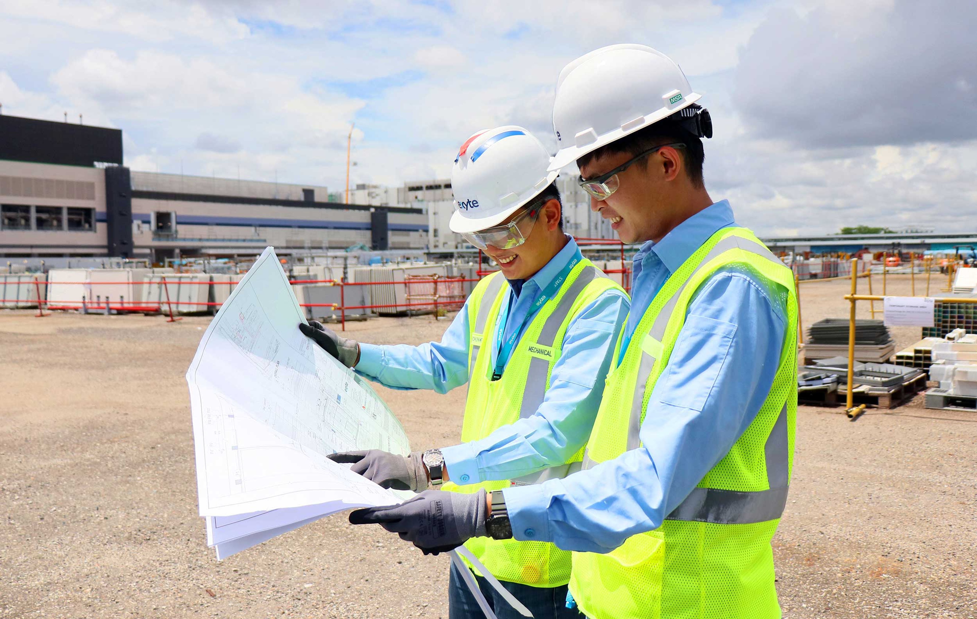 Exyte employees on a project site studying a construction plan