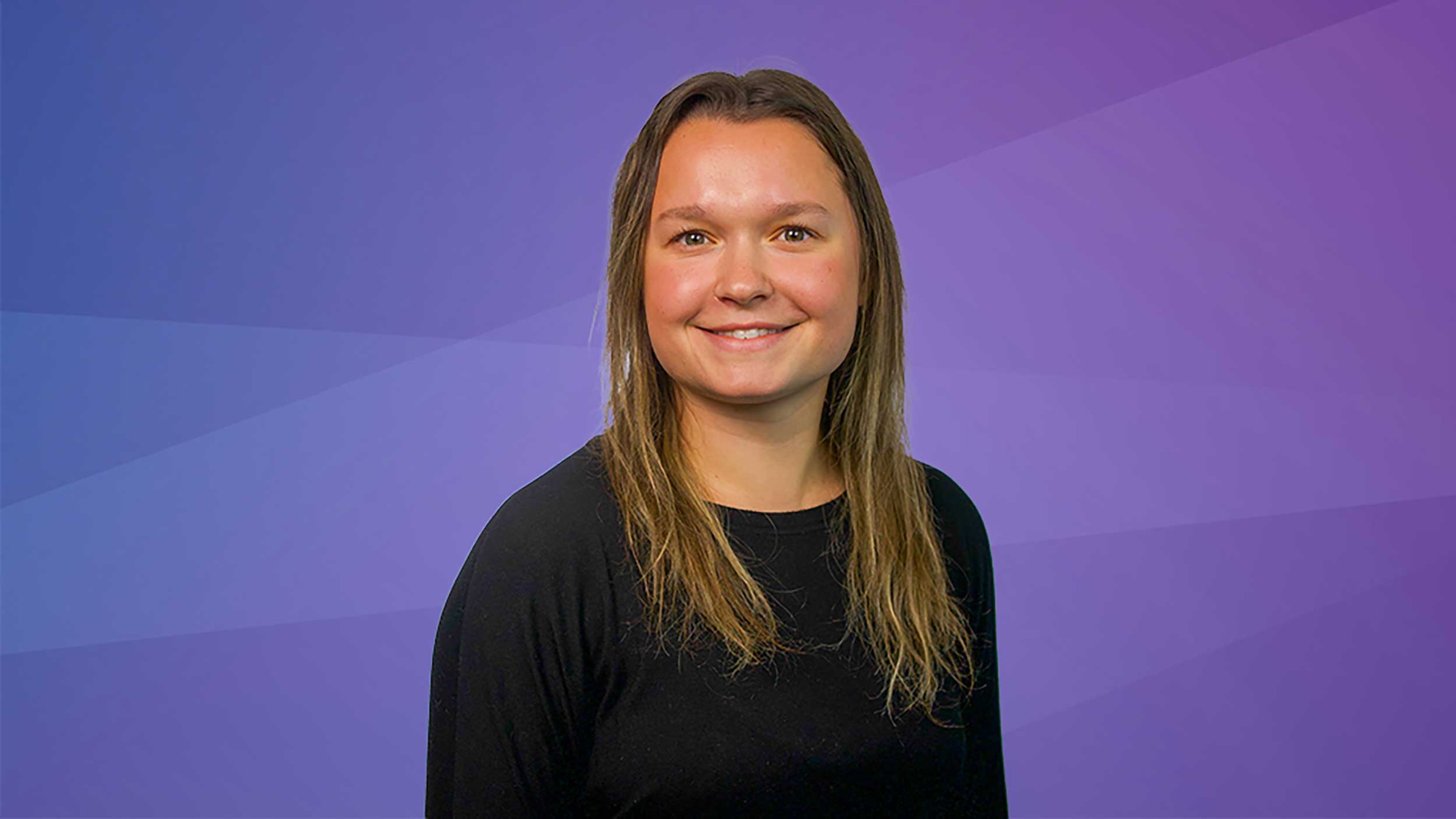 Allison McLaughlin, Process Engineer at Exyte, smiling at her workstation in Albany, USA, where she designs chemical and gas systems for semiconductor manufacturing.