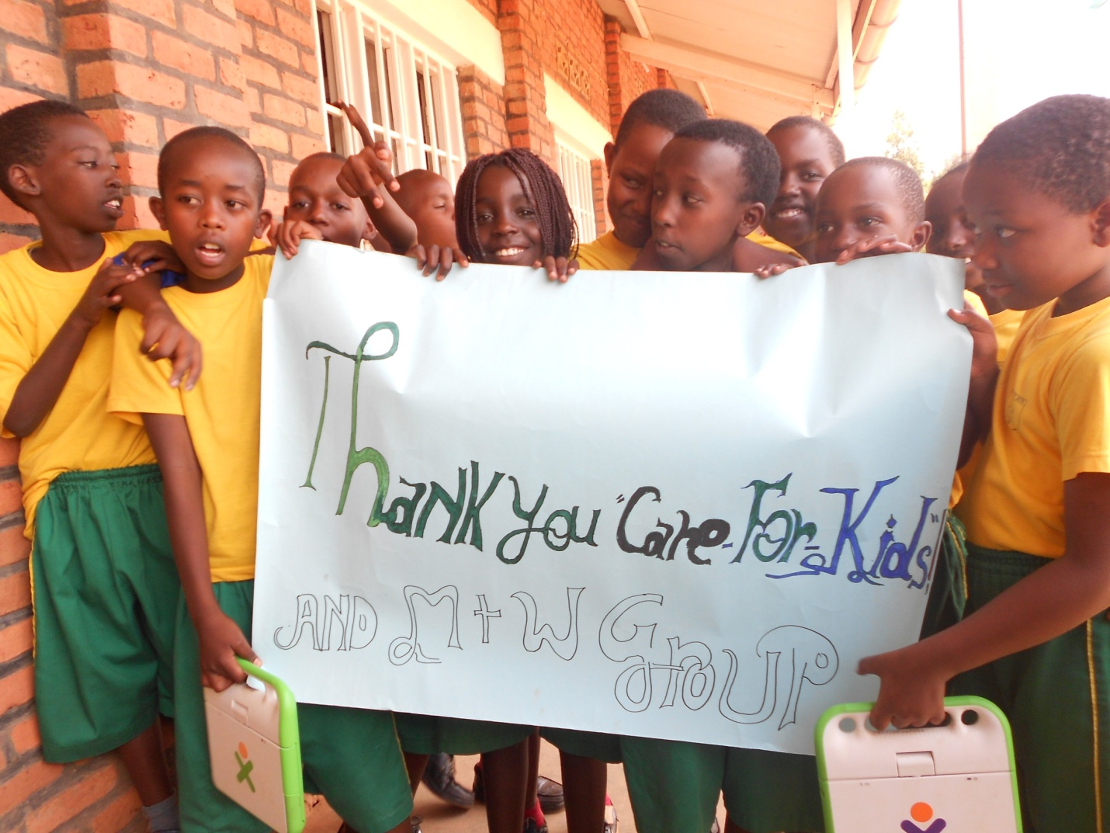 Children hold up a sign with a thank you note mentioning charity organization "Care for Kids"