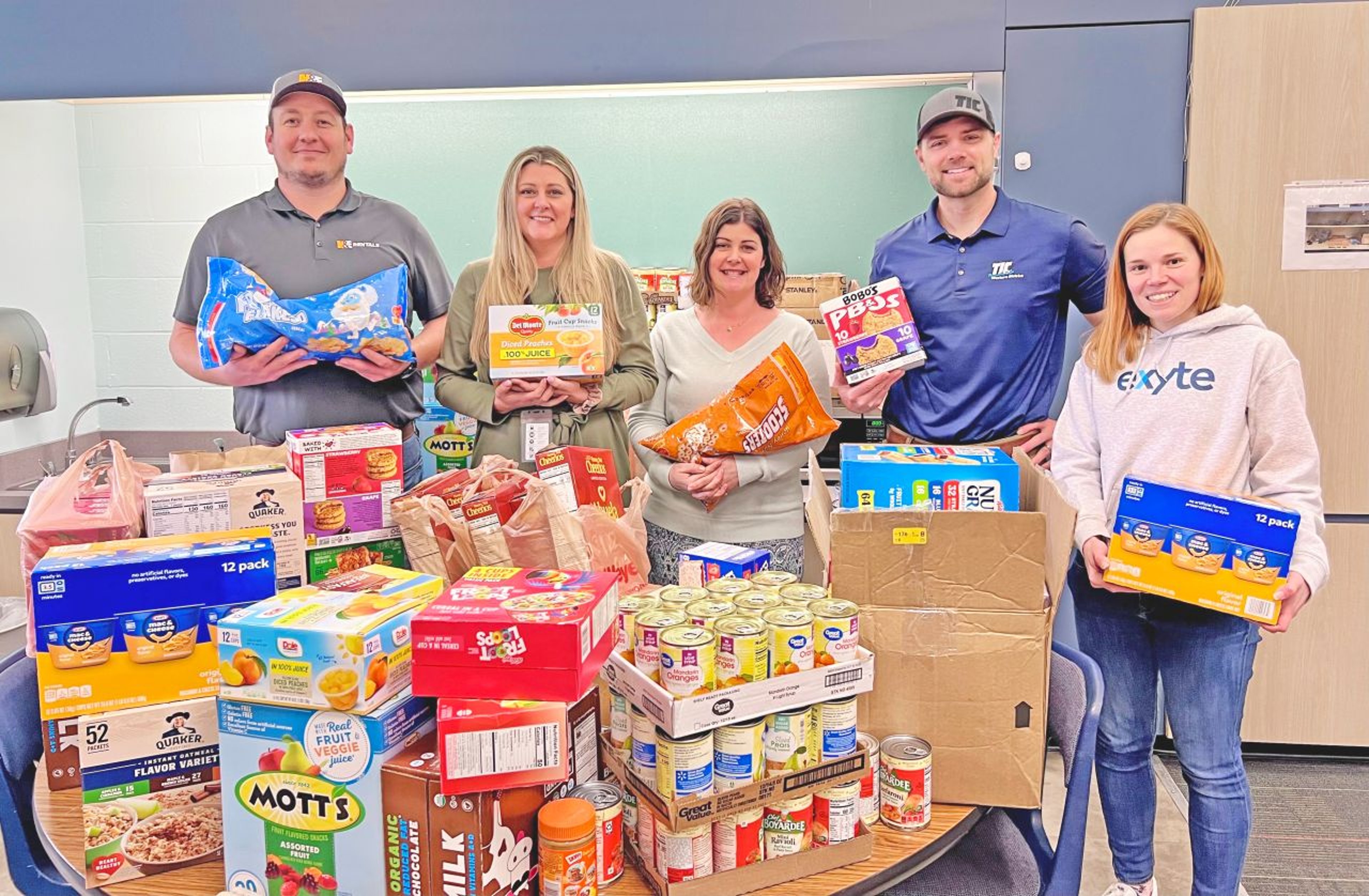Exyte employees pose for a photo with food parcels for a food bank initiative