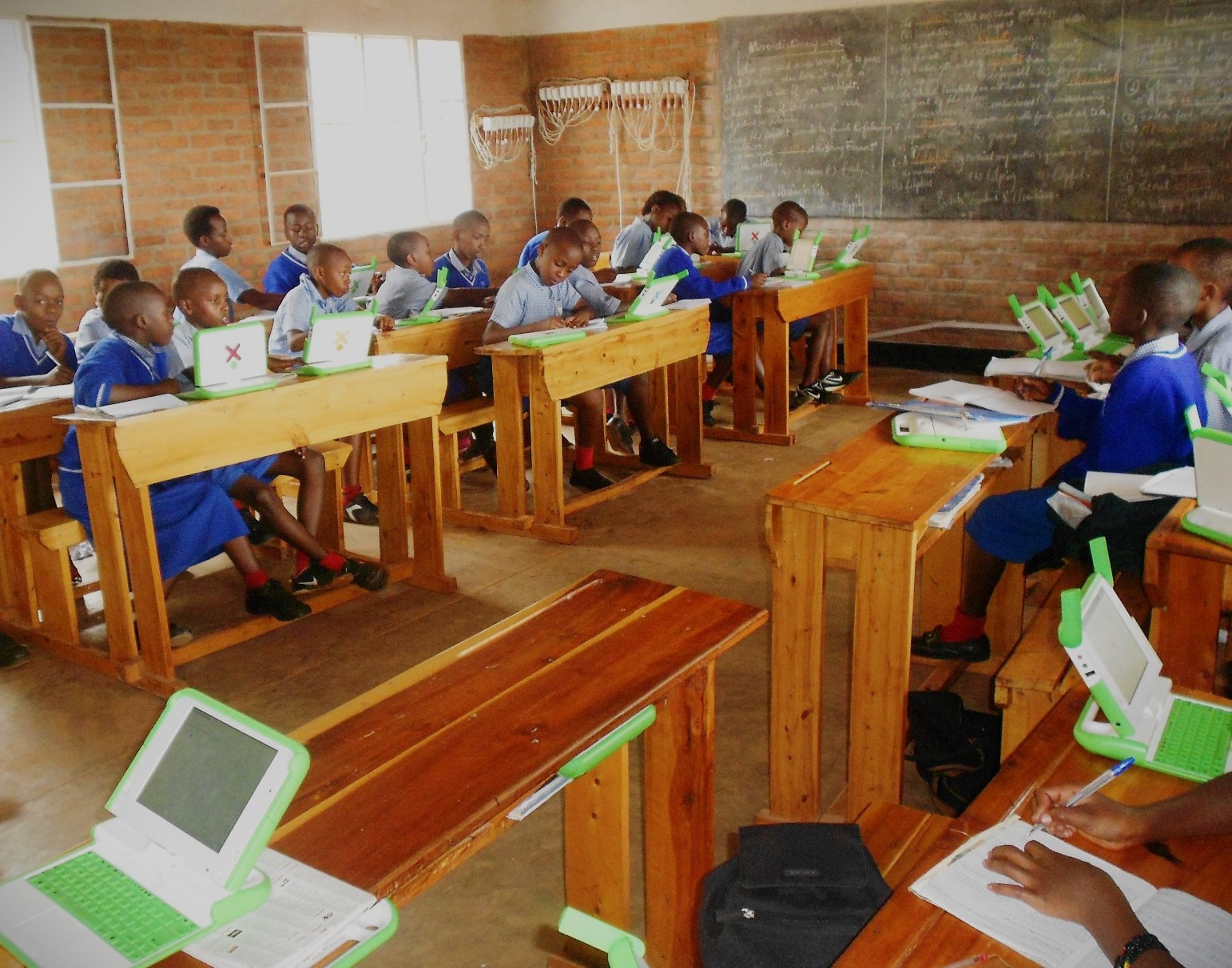 Children sitting in a classroom with laptops sponsored by a charity organization