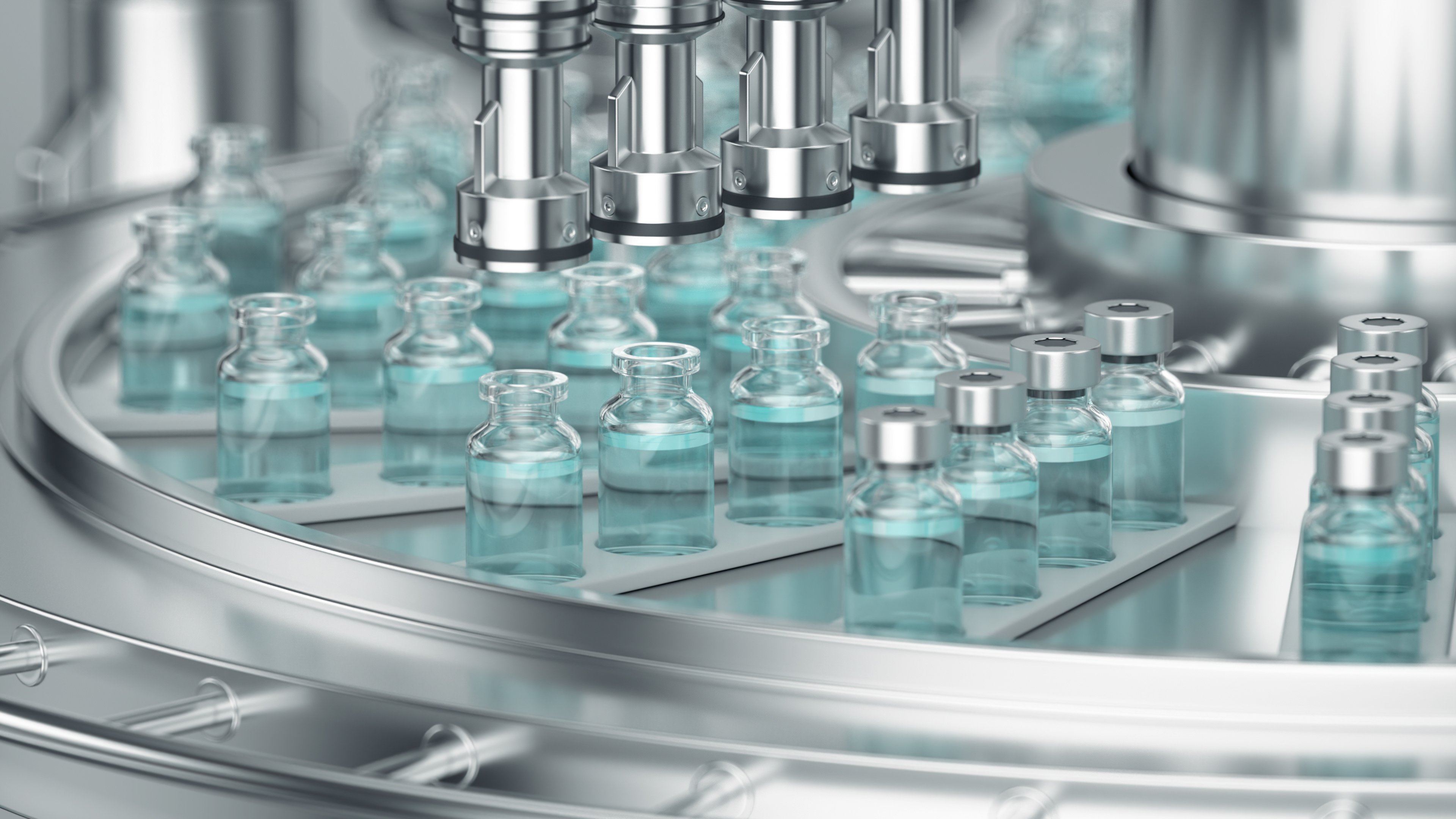 The image shows a production line of mRNA vaccine vials. Small glass vials filled with liquid are being moved through an automated stainless steel filling machine. The equipment appears clean and precise, typical of pharmaceutical manufacturing environments.