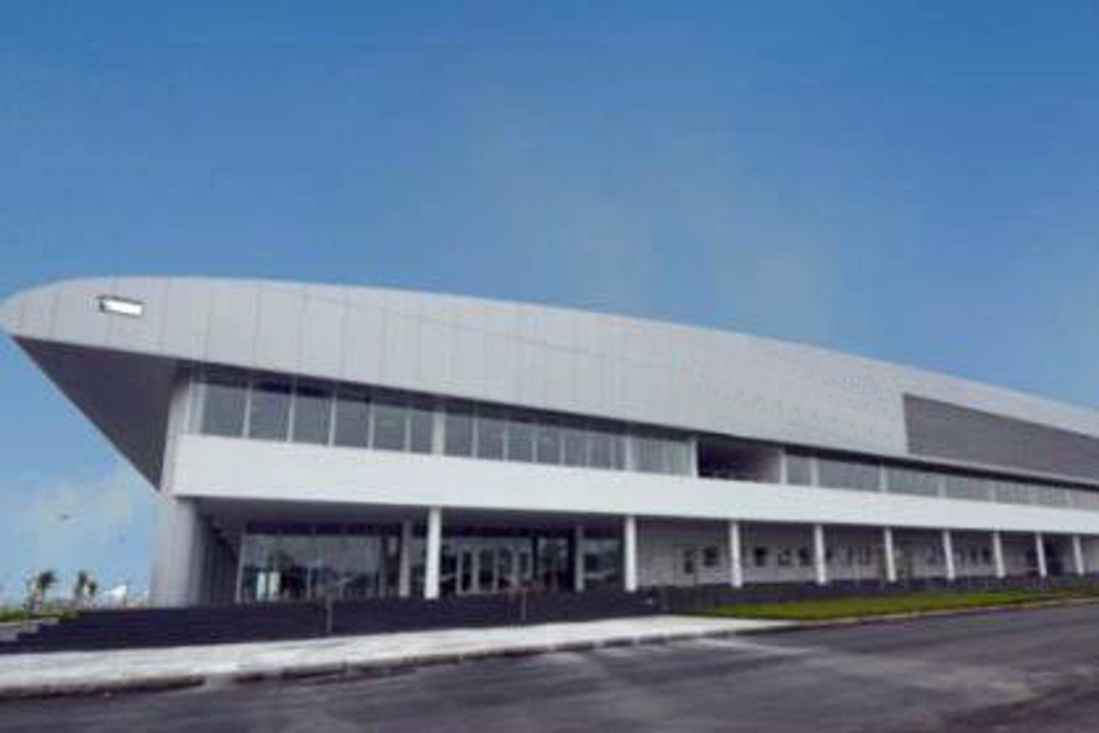 An exterior view of a modern medical device plant in Vietnam, featuring a sleek, curved roof design and large glass windows at the front entrance.
