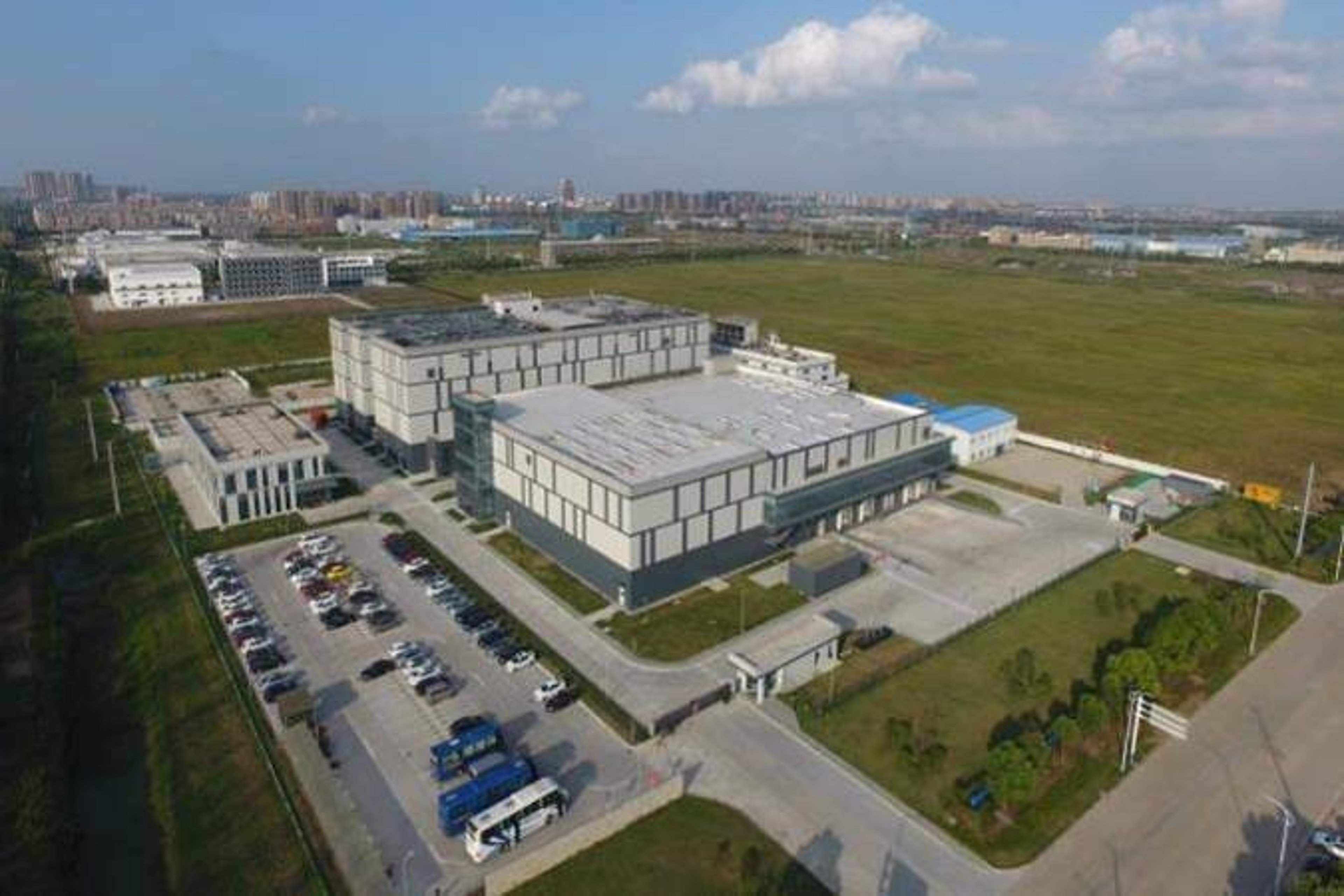 An aerial view of an oral solid dosage facility in Nantong, featuring multiple modern buildings, parking areas, and green open spaces surrounding the complex.