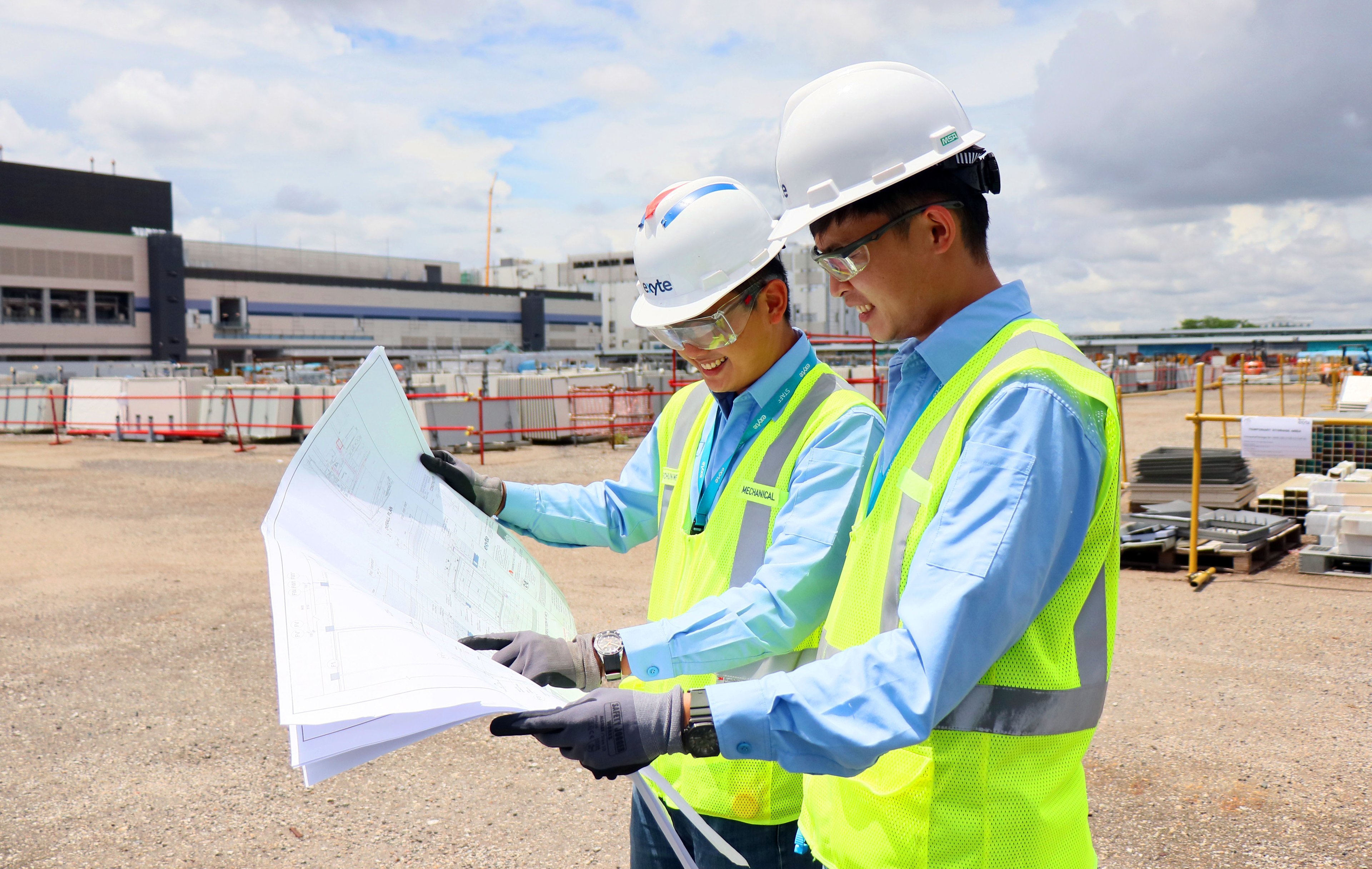 Exyte employees on a project site studying a construction plan