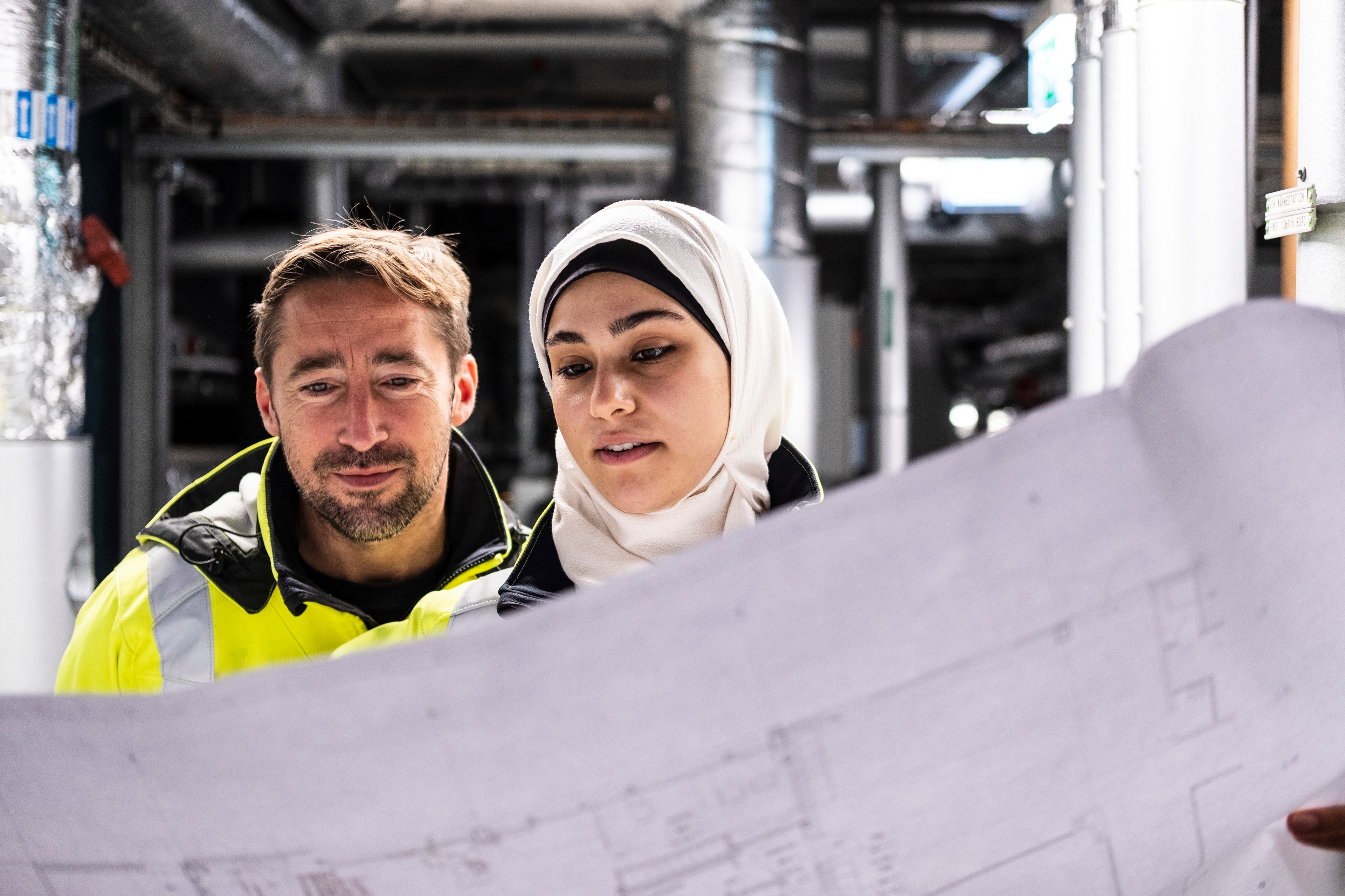 A male and a female engineer look at a plan