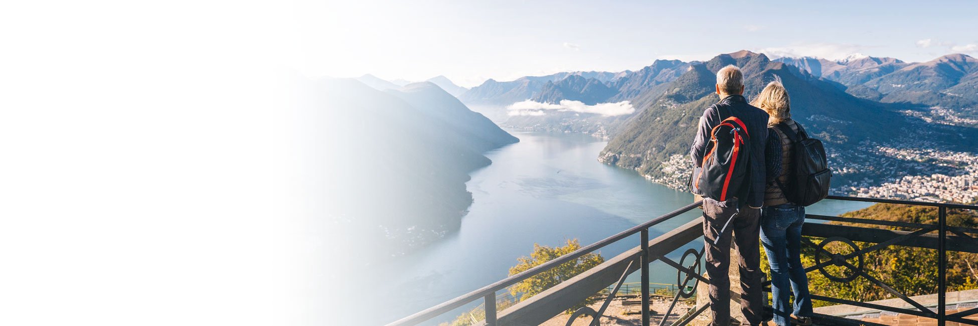 A couple overlooking a beautiful vista high above a large body of water.