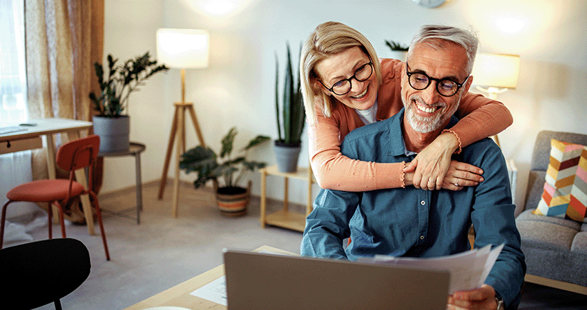 older couple sitting in front of a computer looking at paperwork