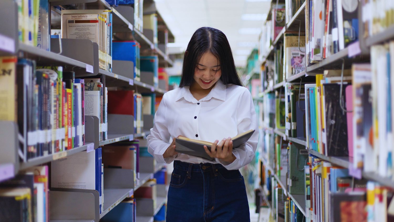 A young woman browsing through a bookshelf in a library, deeply engaged in selecting a book to read