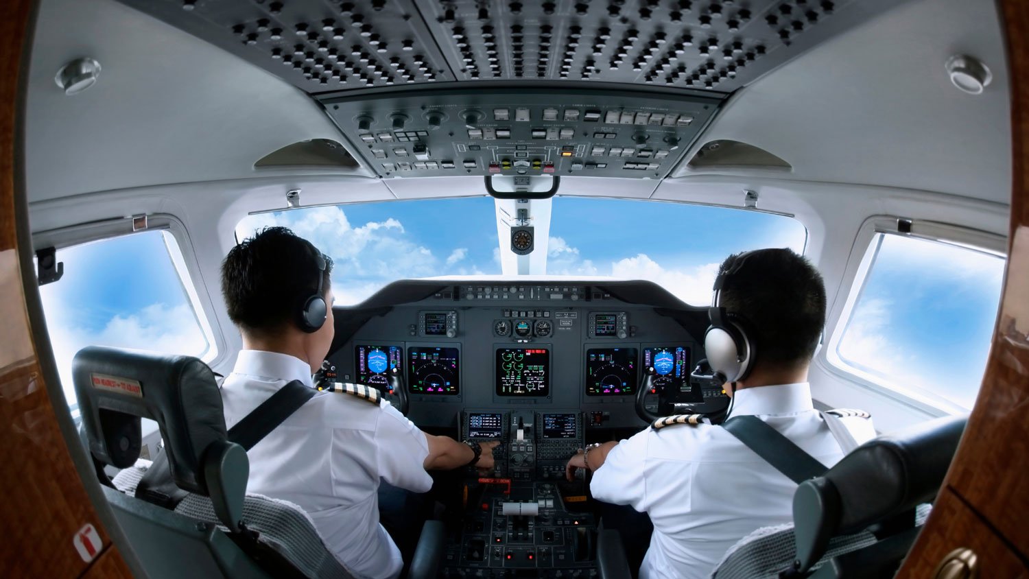 Two pilots operating the cockpit of an airplane.