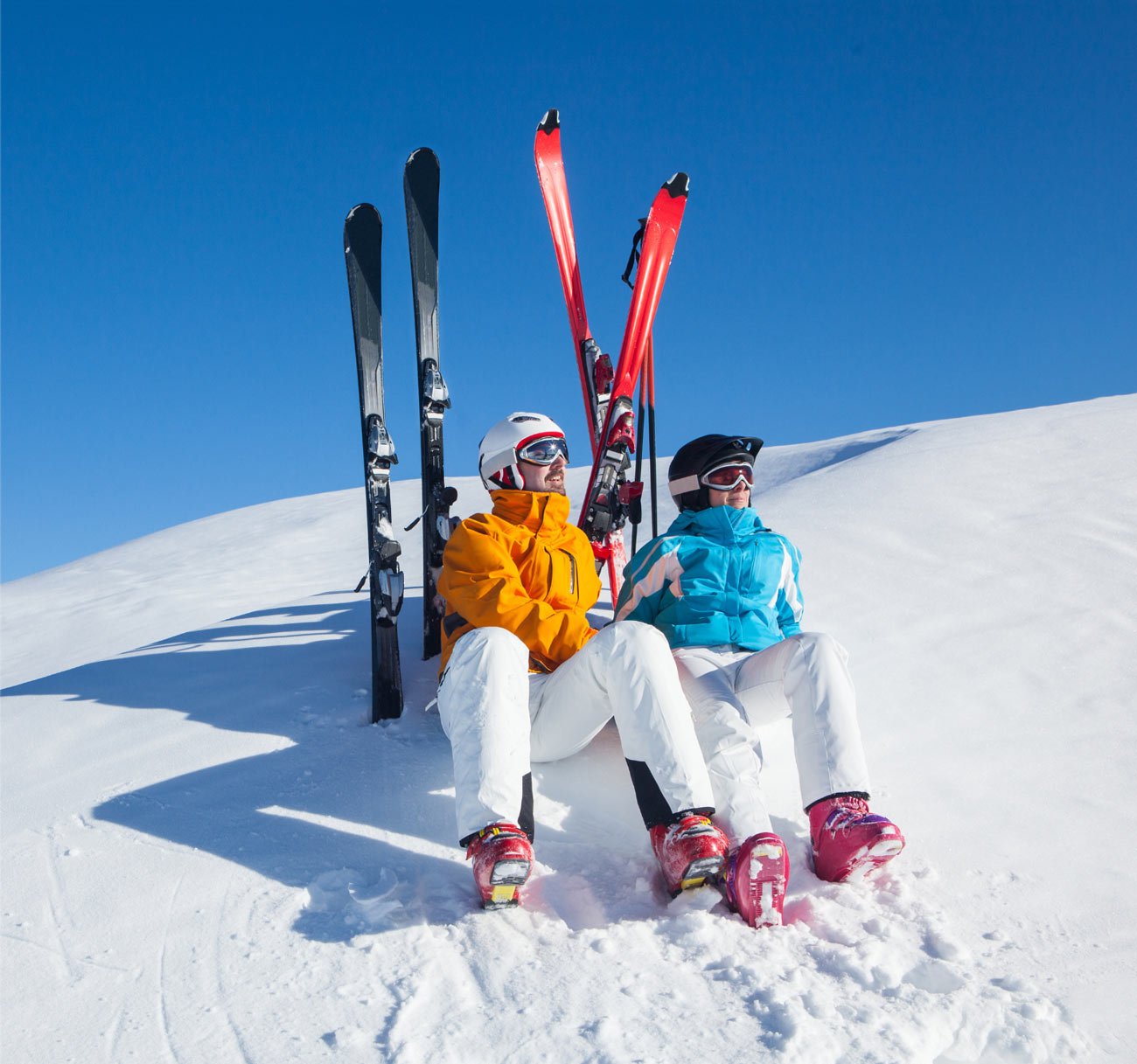 Two skiers sitting on the side of a mountain