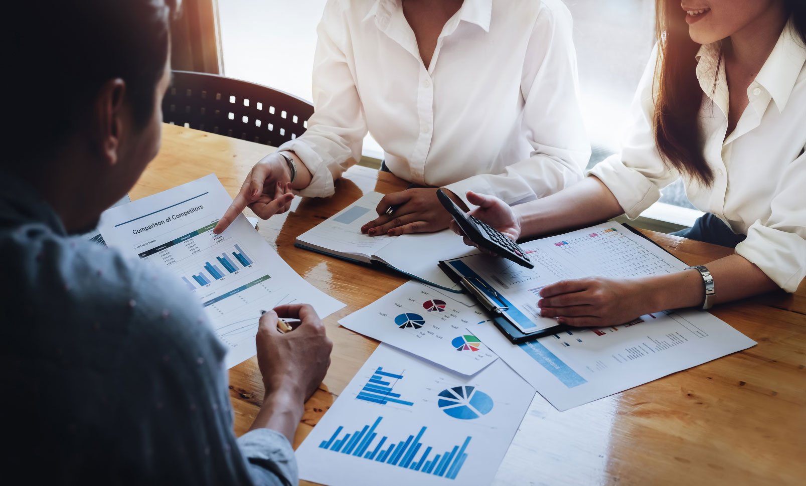 Three professionals discussing charts and graphs during a meeting.