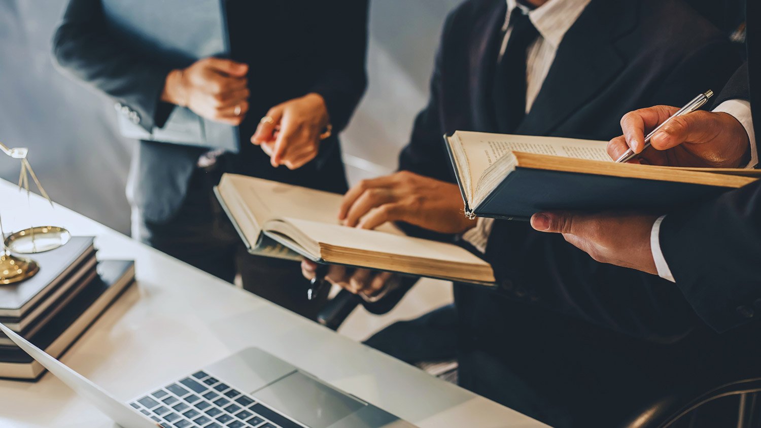 Professionals in suits reviewing books and documents at a table