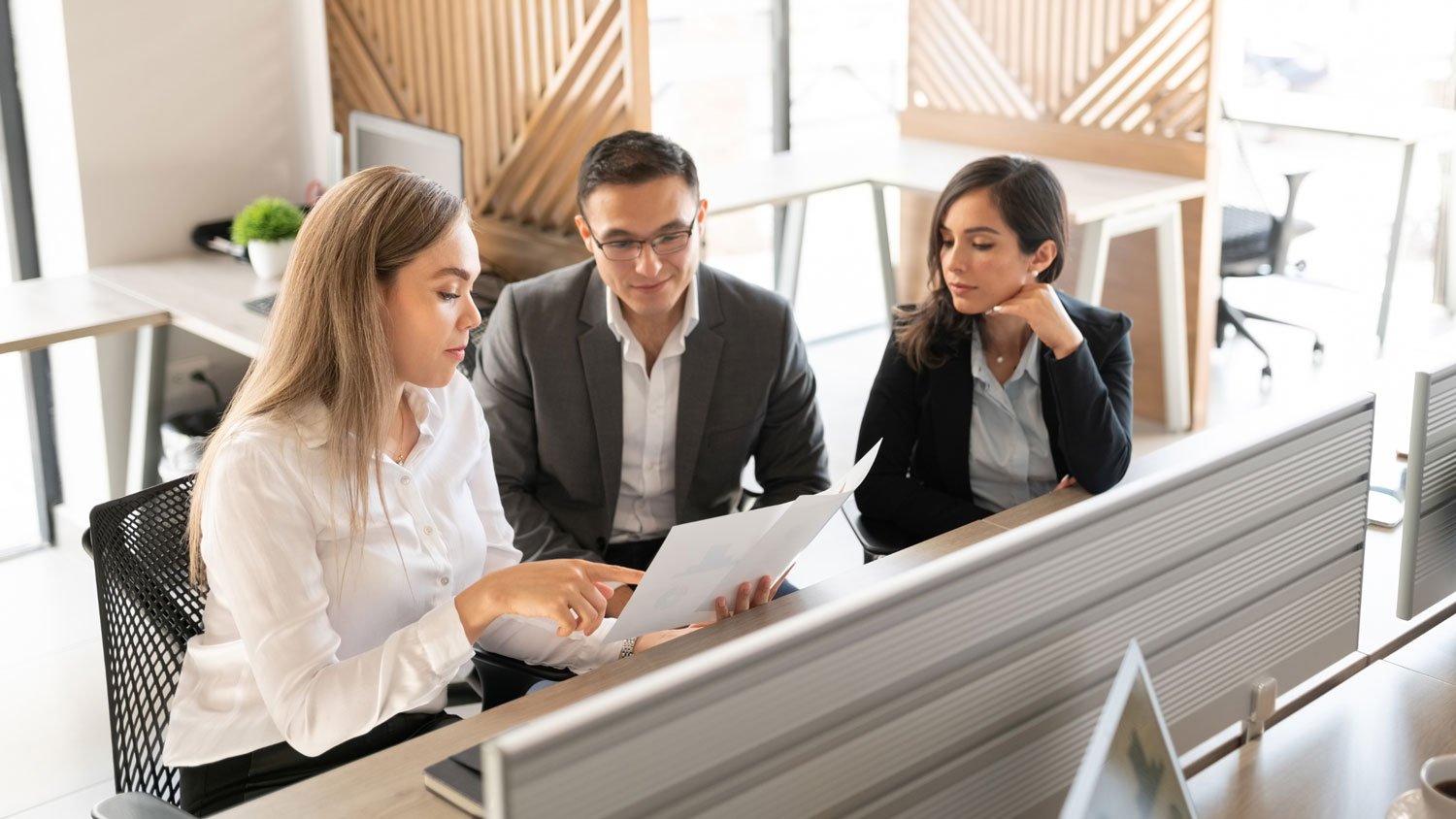 Three professionals discussing legal documents in an office setting
