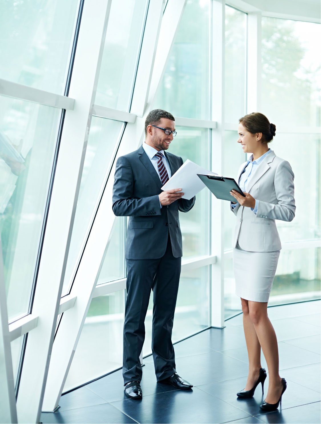 Two legal professionals, a man and a woman, discussing a legal document in a well-lit office with large windows