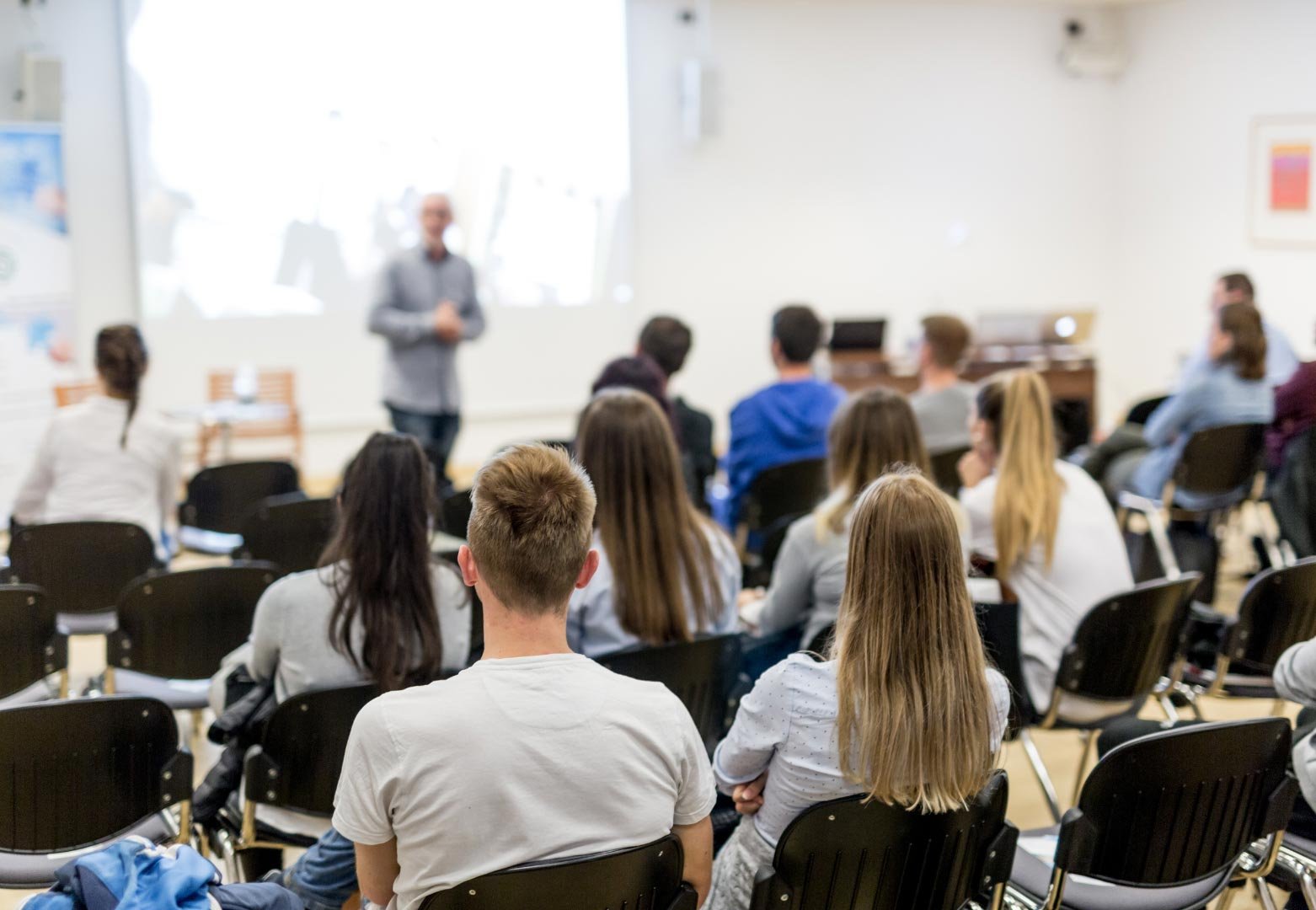 Students sitting in a lecture hall listening attentively to a presenter at the front