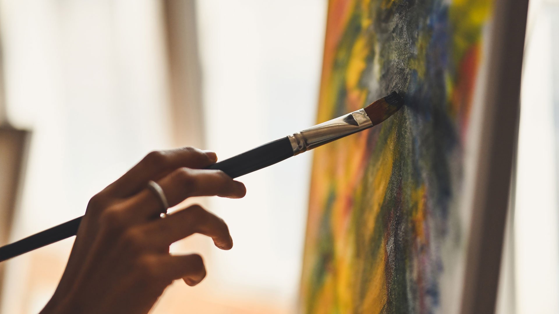 Close-up of a hand painting vibrant colors on a canvas, illustrating the detail in brushwork