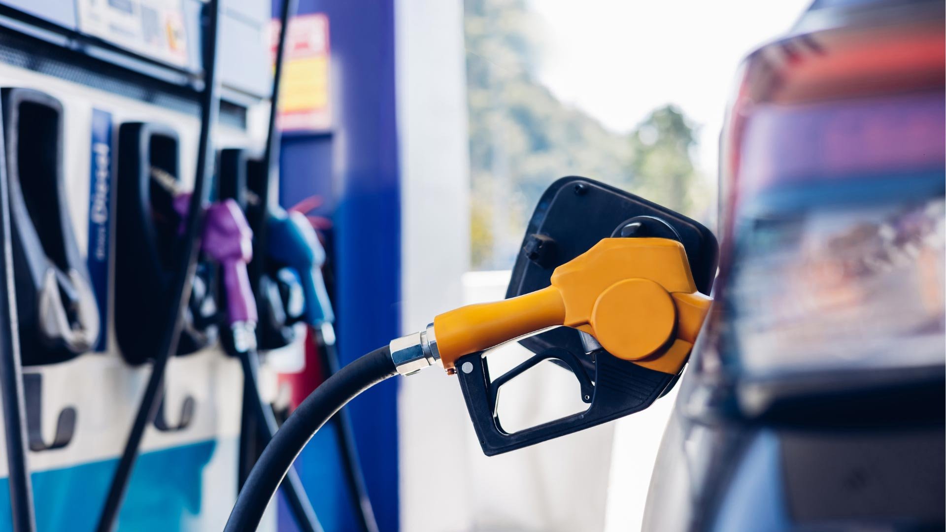 Close-up of a yellow fuel nozzle in a car's fuel tank at a gas station
