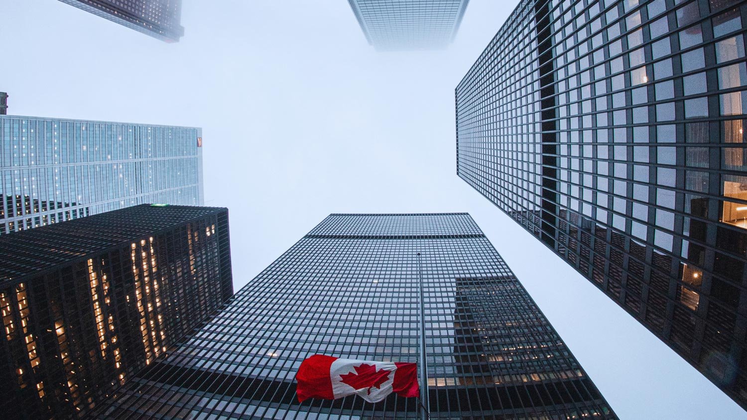 Upward view of office building downtown with a Canadian flag