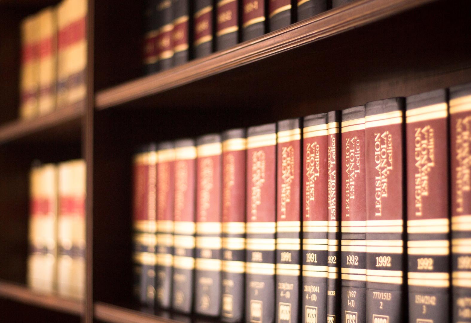 A bookshelf filled with red and gold law books.