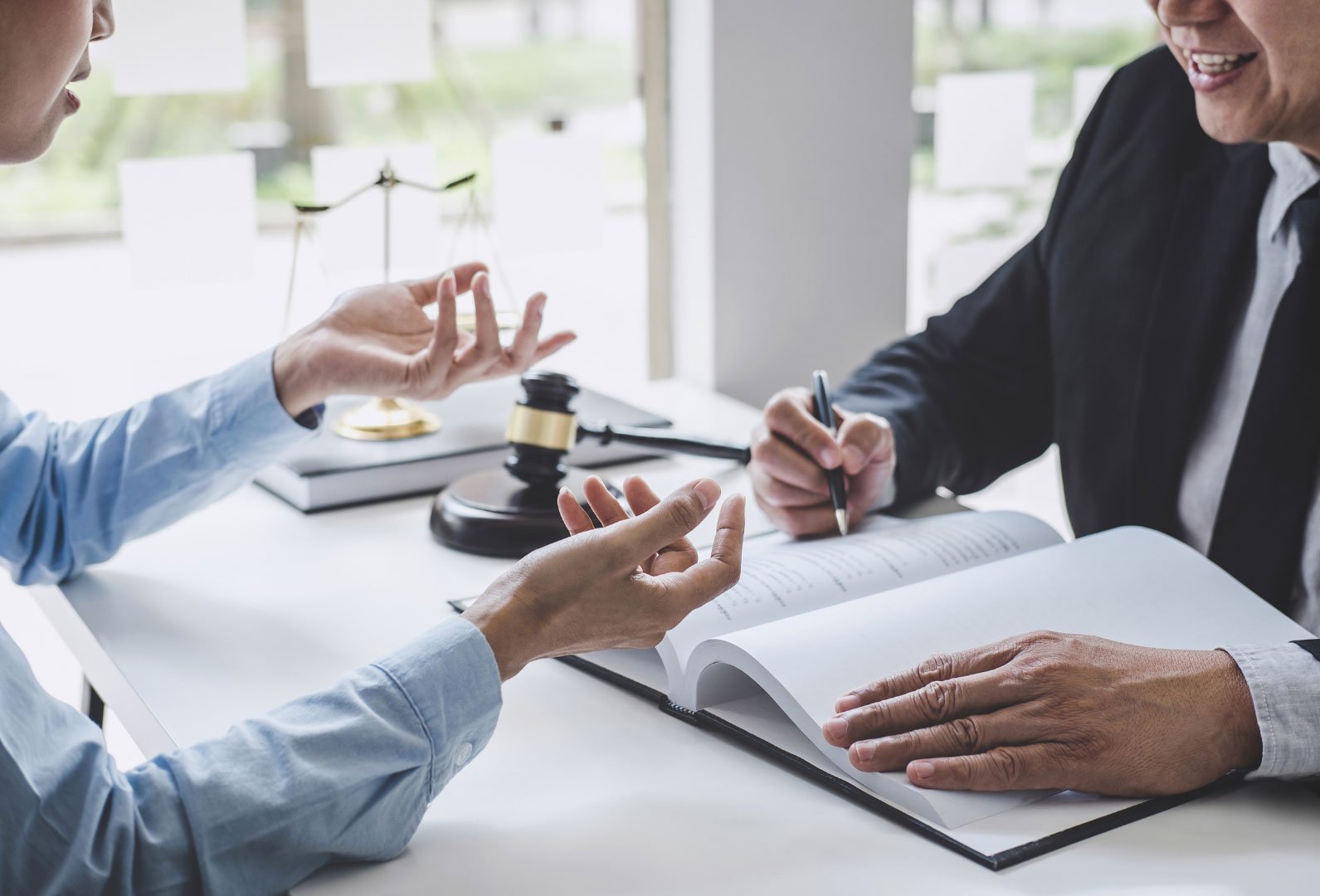 Two people discussing over legal documents beside a judge's gavel.