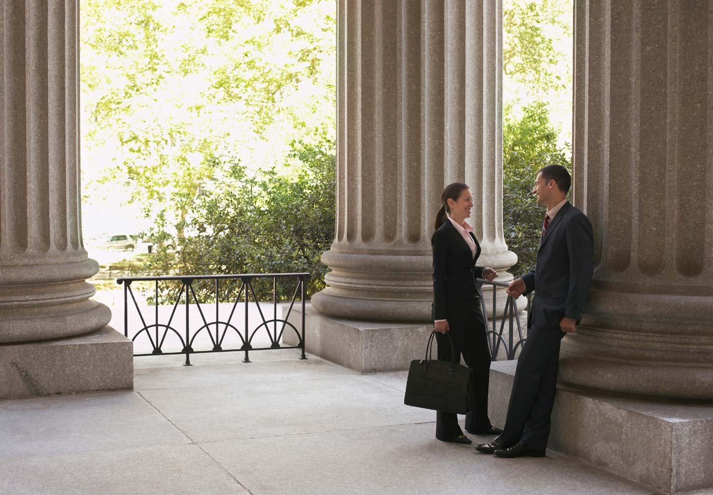 Two lawyers talking in front of classical architecture with columns.