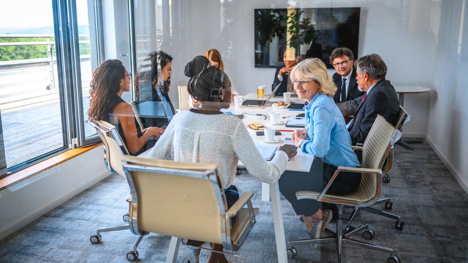 A team of diverse professionals discussing around a conference table in a bright office.
