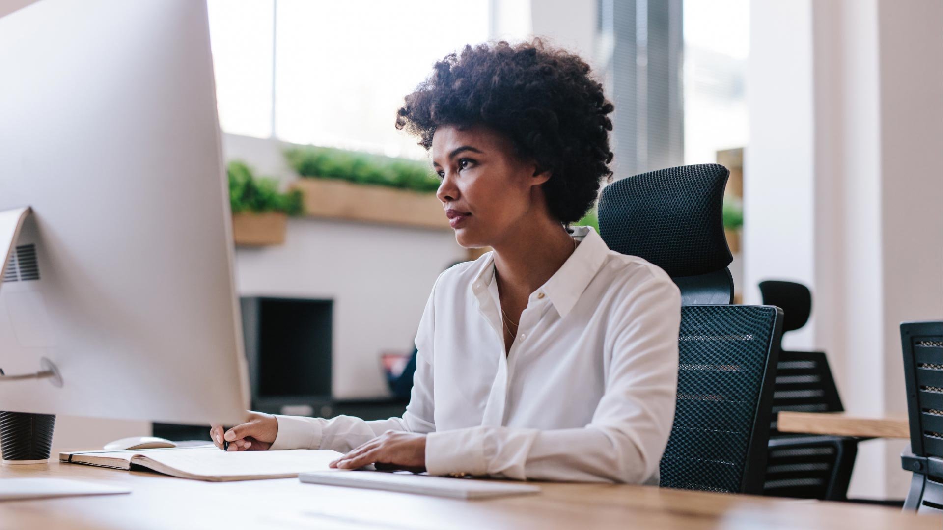 A focused professional woman working at her computer in a modern office.