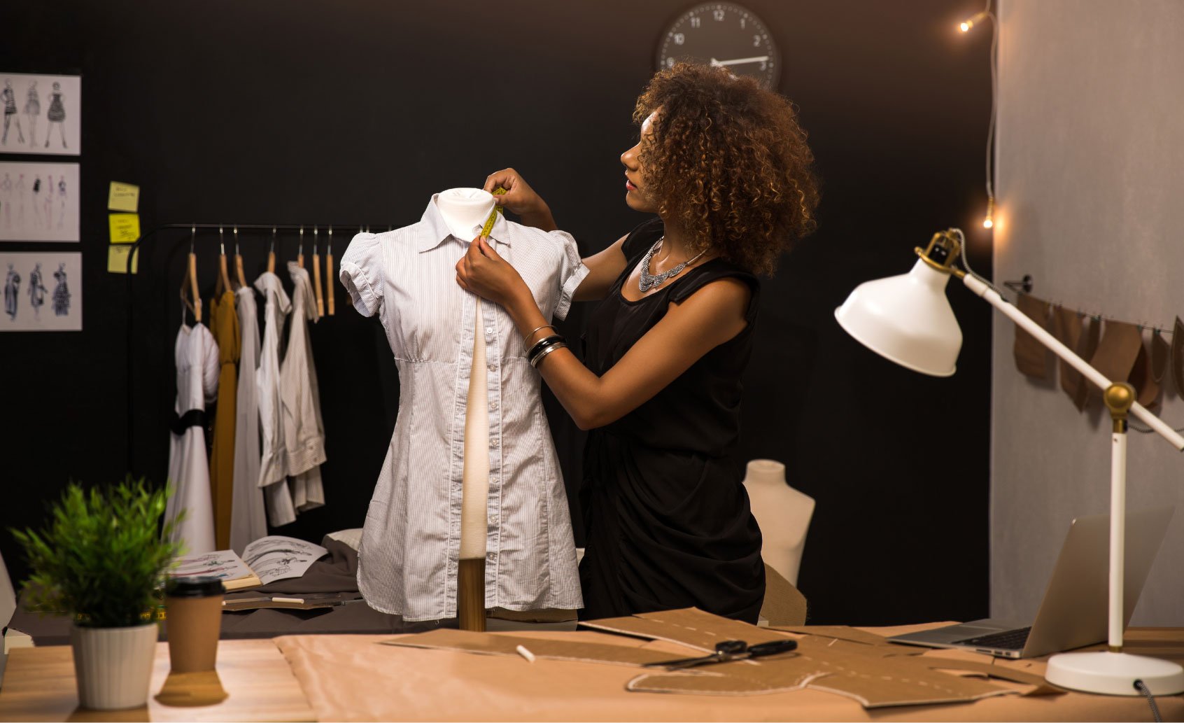 A fashion designer measuring a garment on a mannequin in a well-lit studio.