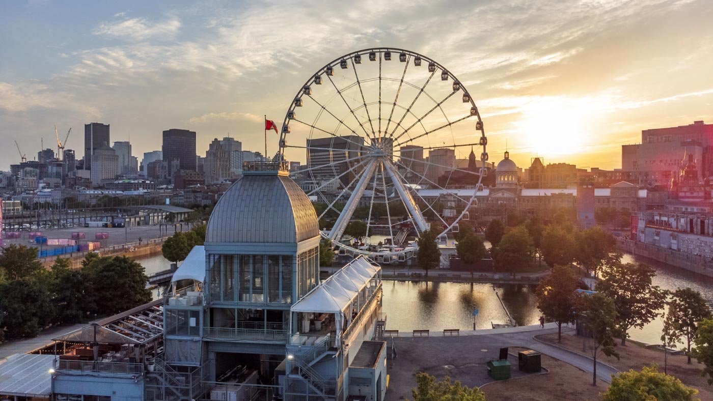 A scenic view of Montreal's skyline with a Ferris wheel at sunset.