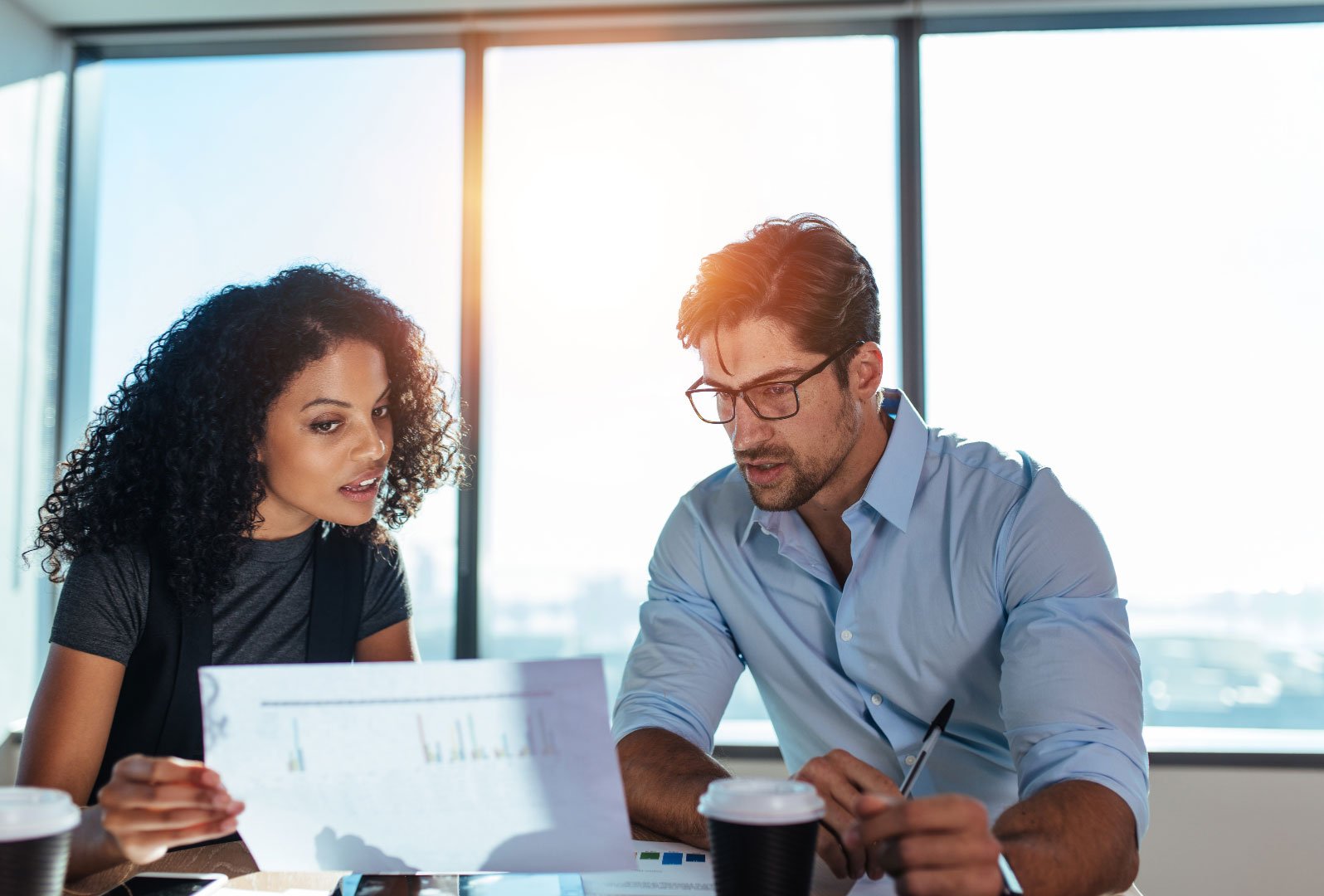 A man and woman discussing financial charts in a bright office setting