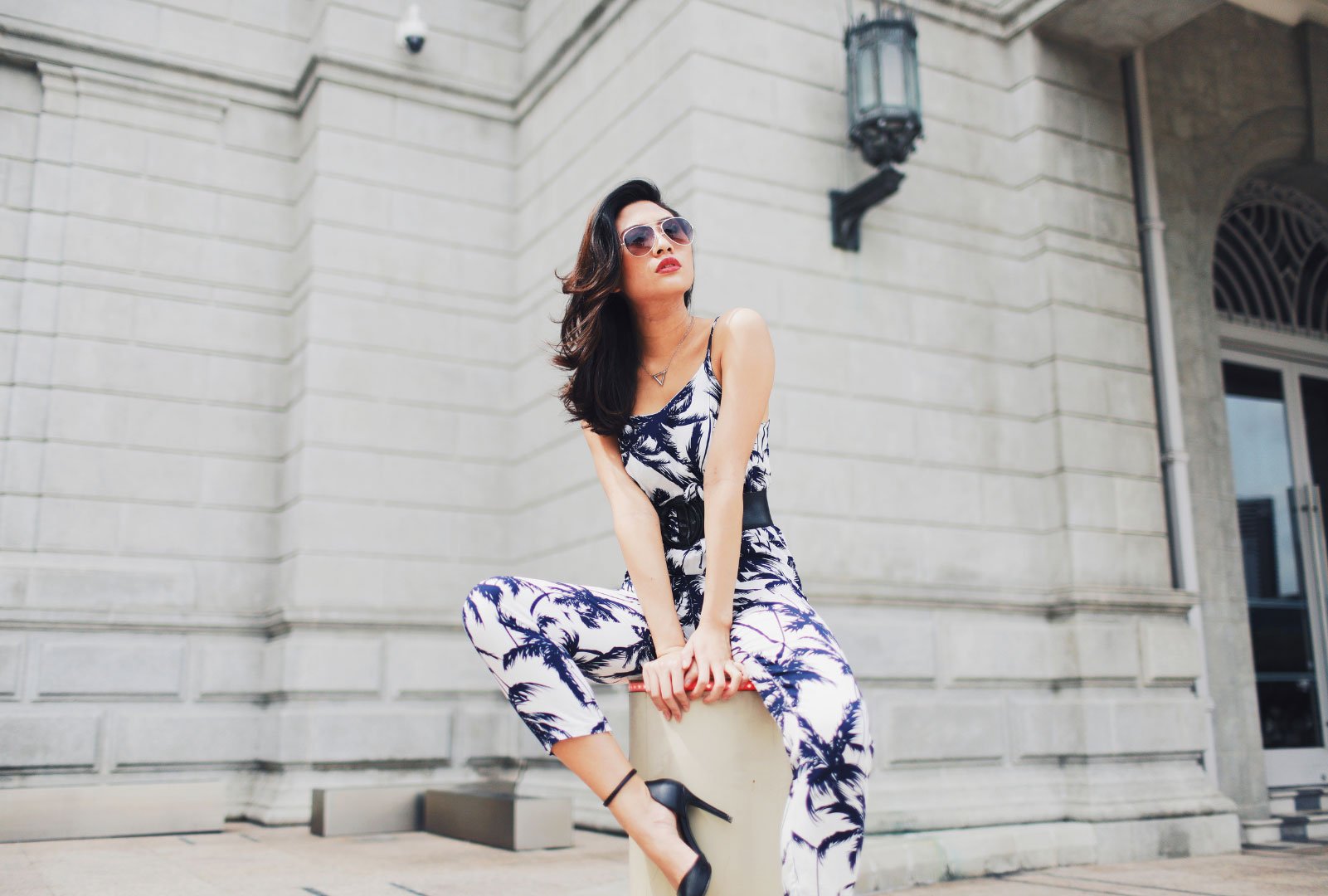 A woman in a stylish black and white jumpsuit posing on a city building's steps