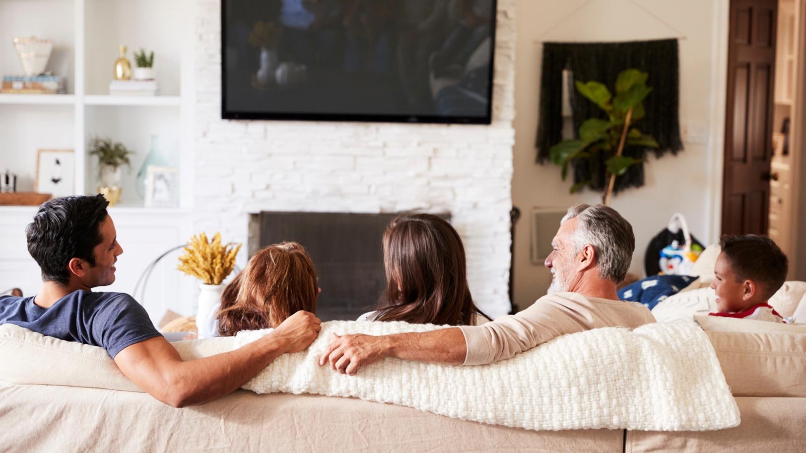 A family of five comfortably watching TV together in a living room