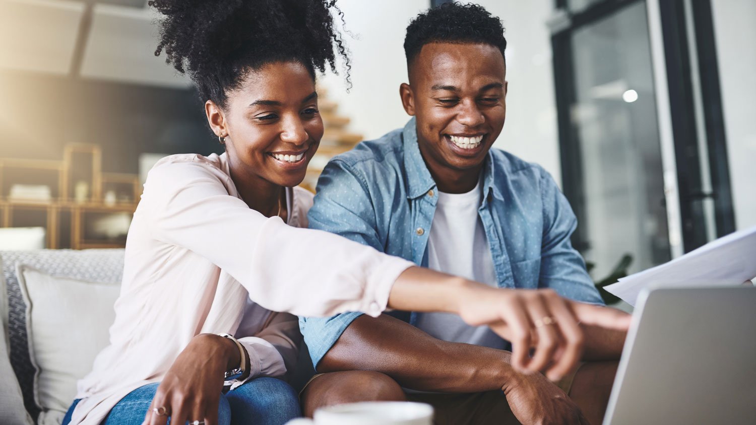 A happy couple using a laptop to manage their finances at home.