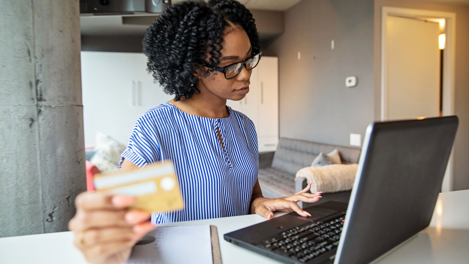 A young woman using a credit card to shop online on her laptop.