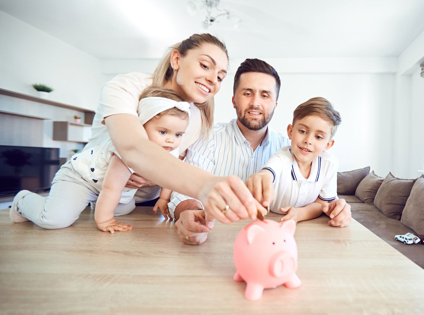 A family teaching their children about saving money using a piggy bank.