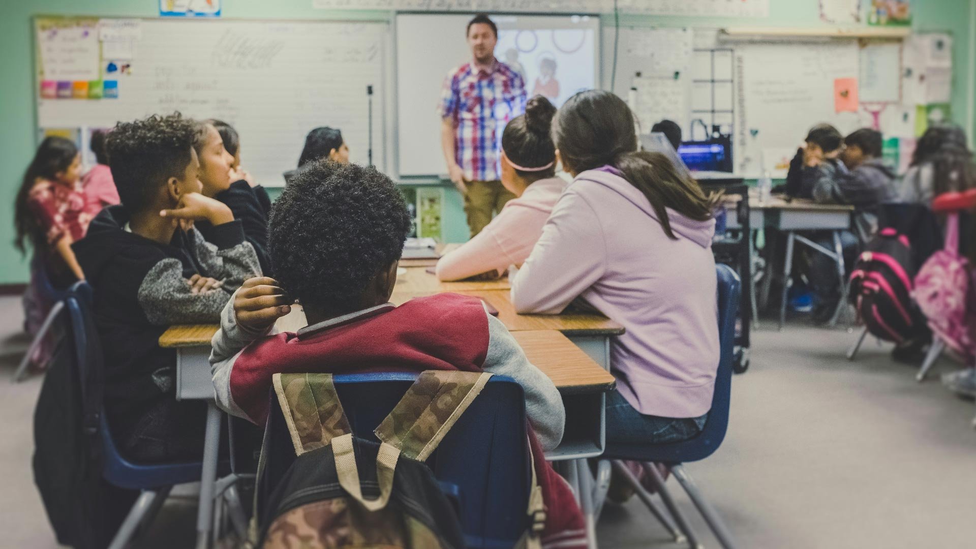 A teacher engages with students of various ethnicities in a lively classroom setting