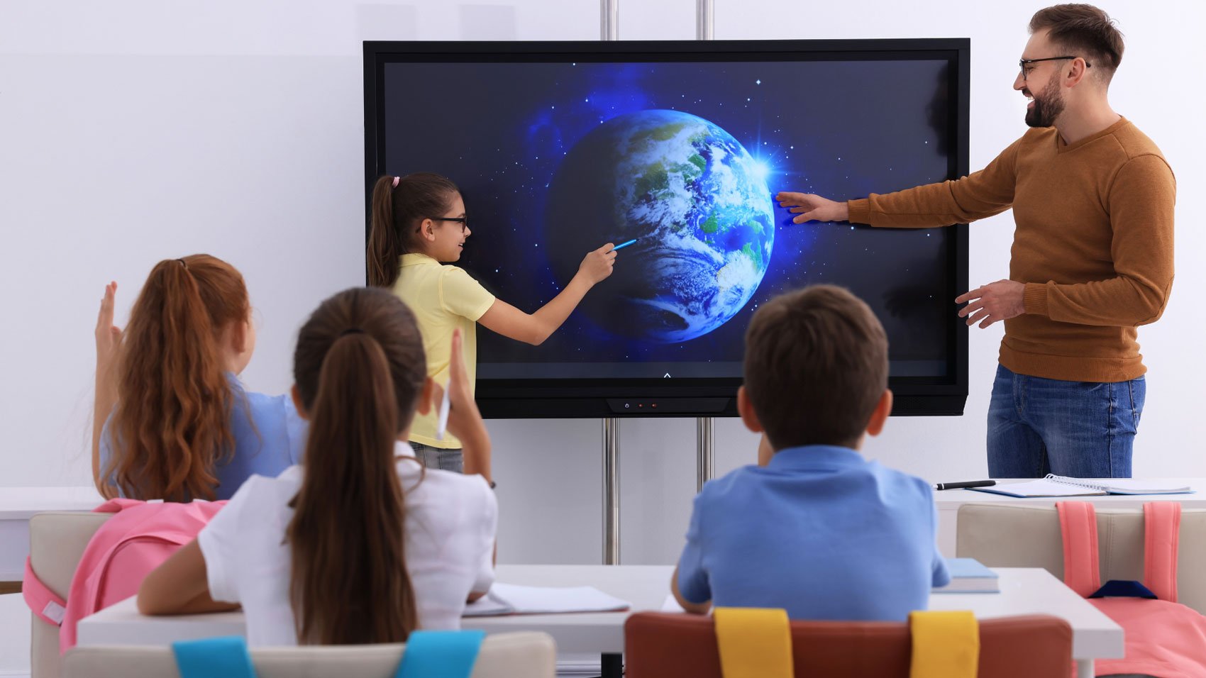 A female student points at a molecular structure on a screen as her teacher looks on