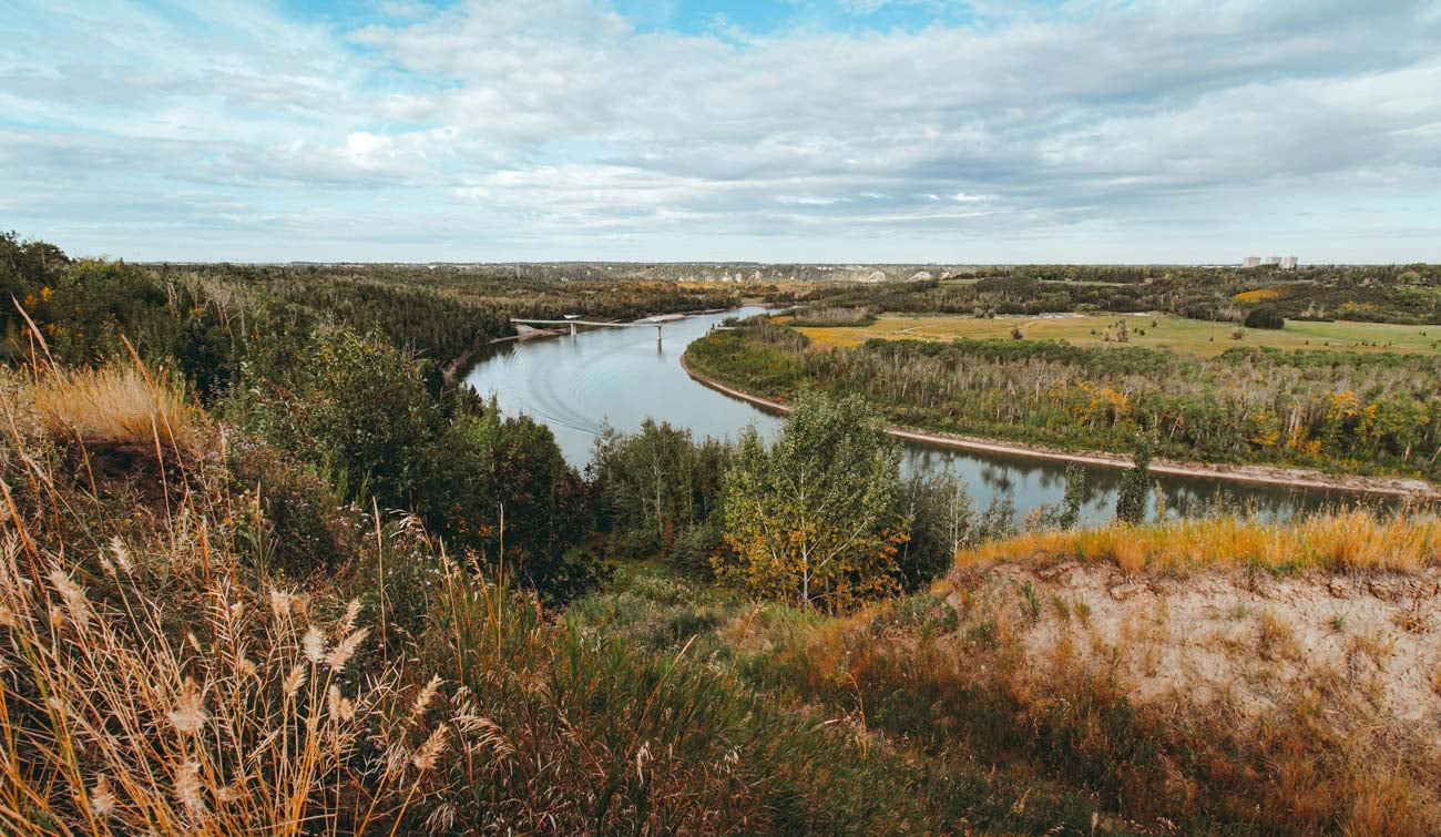 Wide river curving through a lush landscape with a bridge in the distance